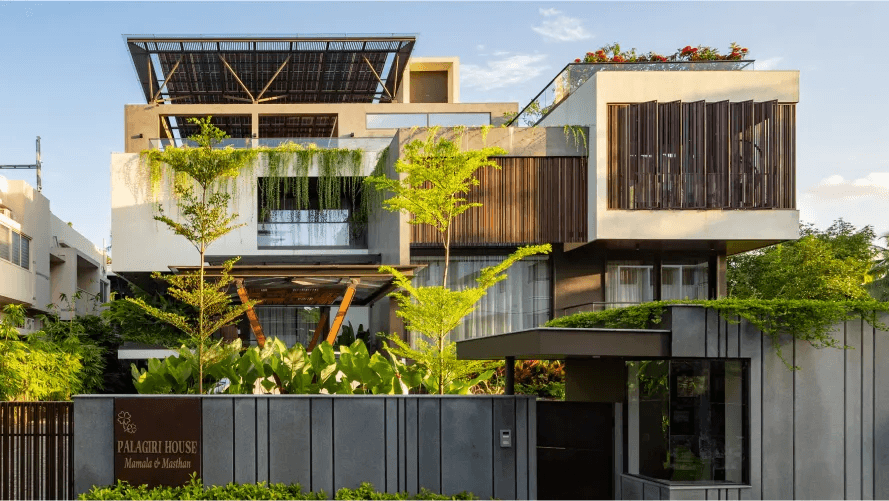 The Palagiri House from the street: timber screens, a rooftop solar pergola, planting along the compound wall and the name wall at the gate