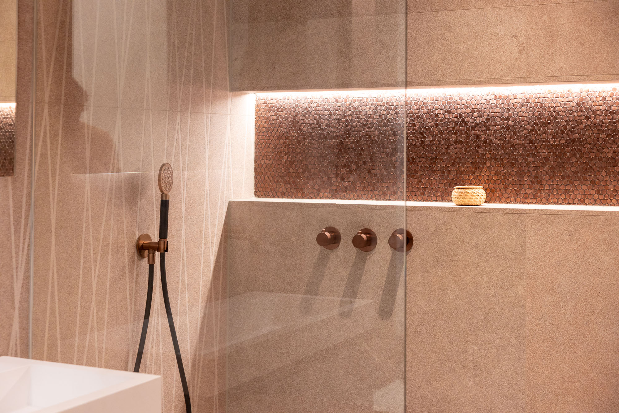 Young man in a green hoodie holding a yellow phone while seated at a table with a tablet.