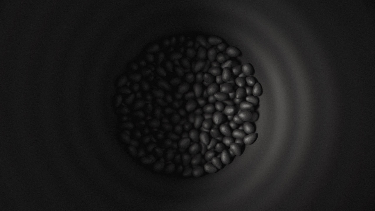 A top-down, high-contrast view looking inside a dark funnel hopper filled with oval-shaped thermoplastic pellets, the raw material used for FGF (Fused Granulate Fabrication) 3D printing.
