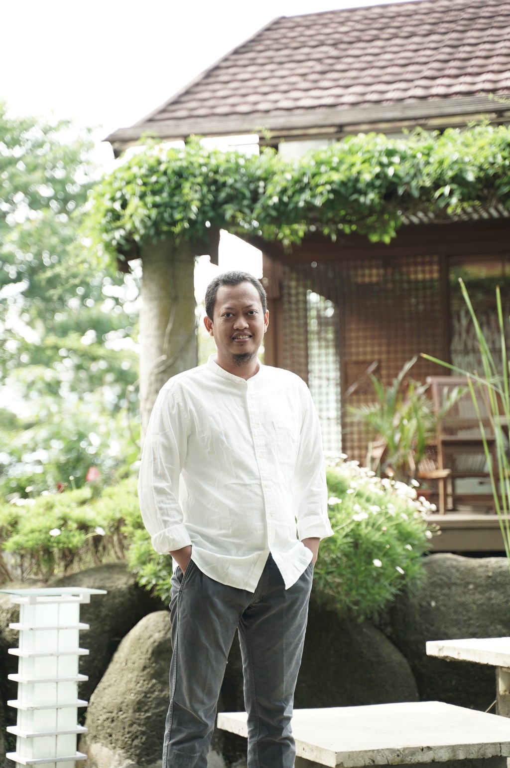 A winding road cuts through rocky terrain, surrounded by patches of green grass and illuminated by sunlight.