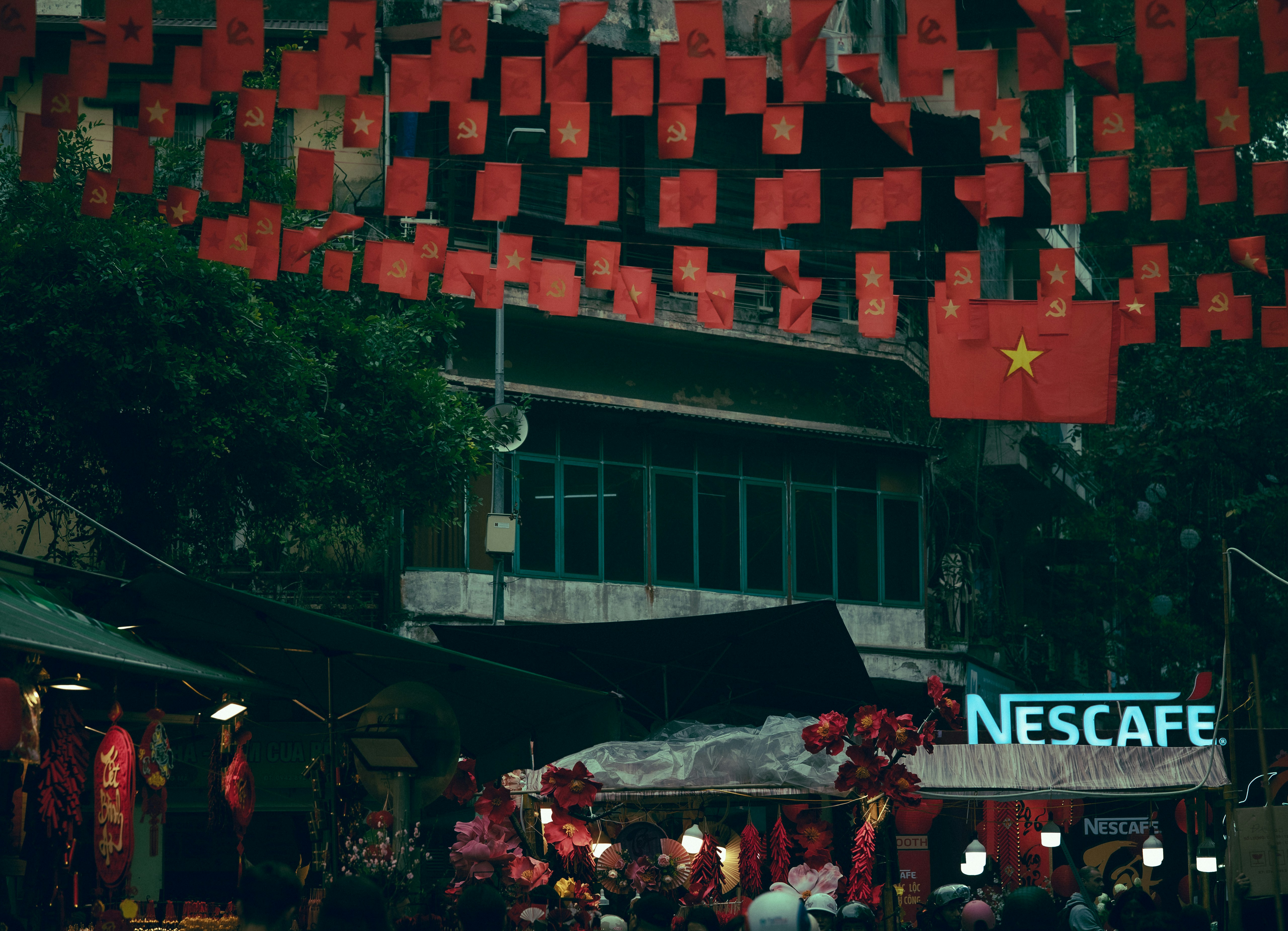 Red flags and nescafe sign in bustling street market