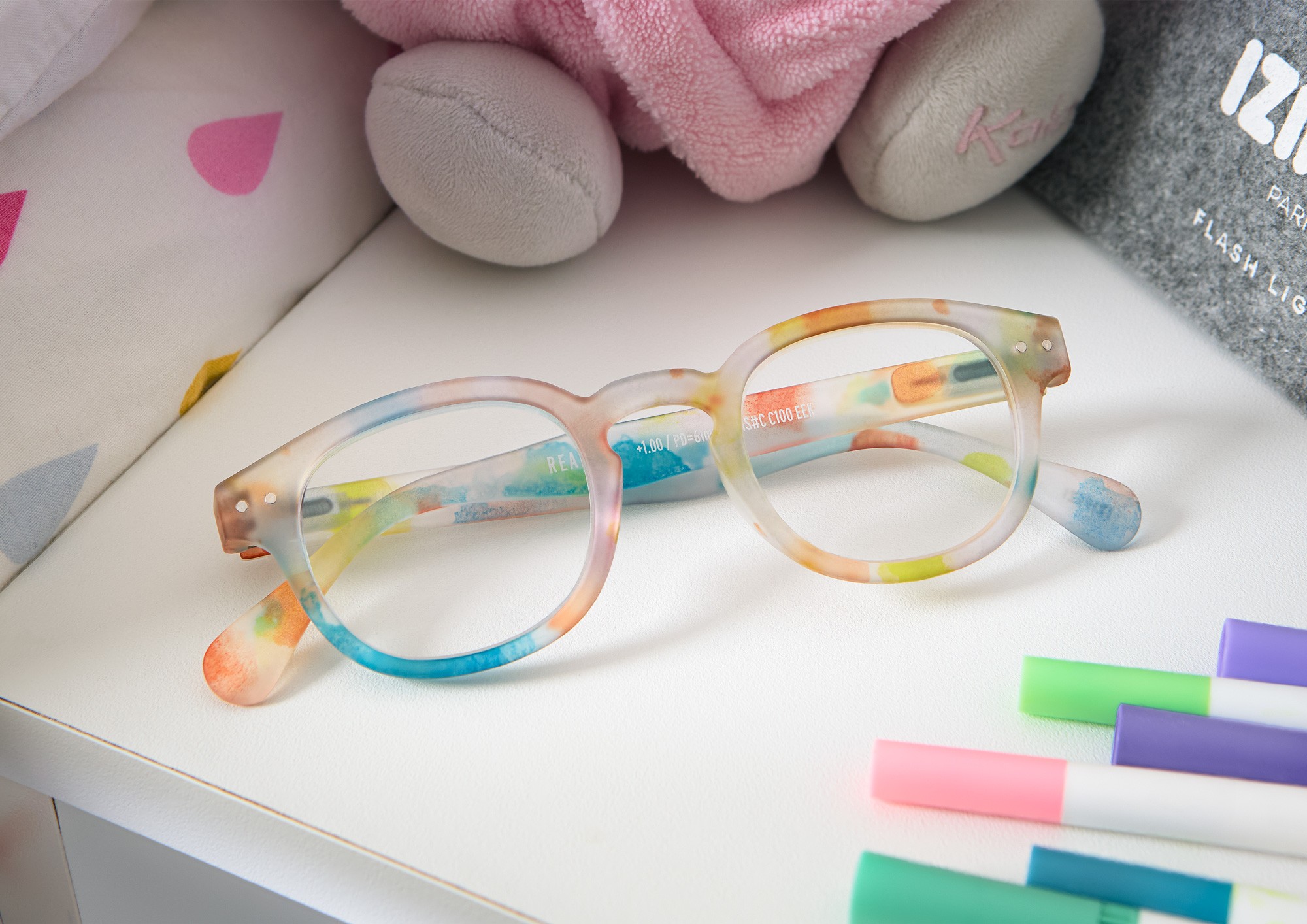 Colourful speckeled Izipizi glasses on a childs nightstand. Photographed by Matthew Brown.