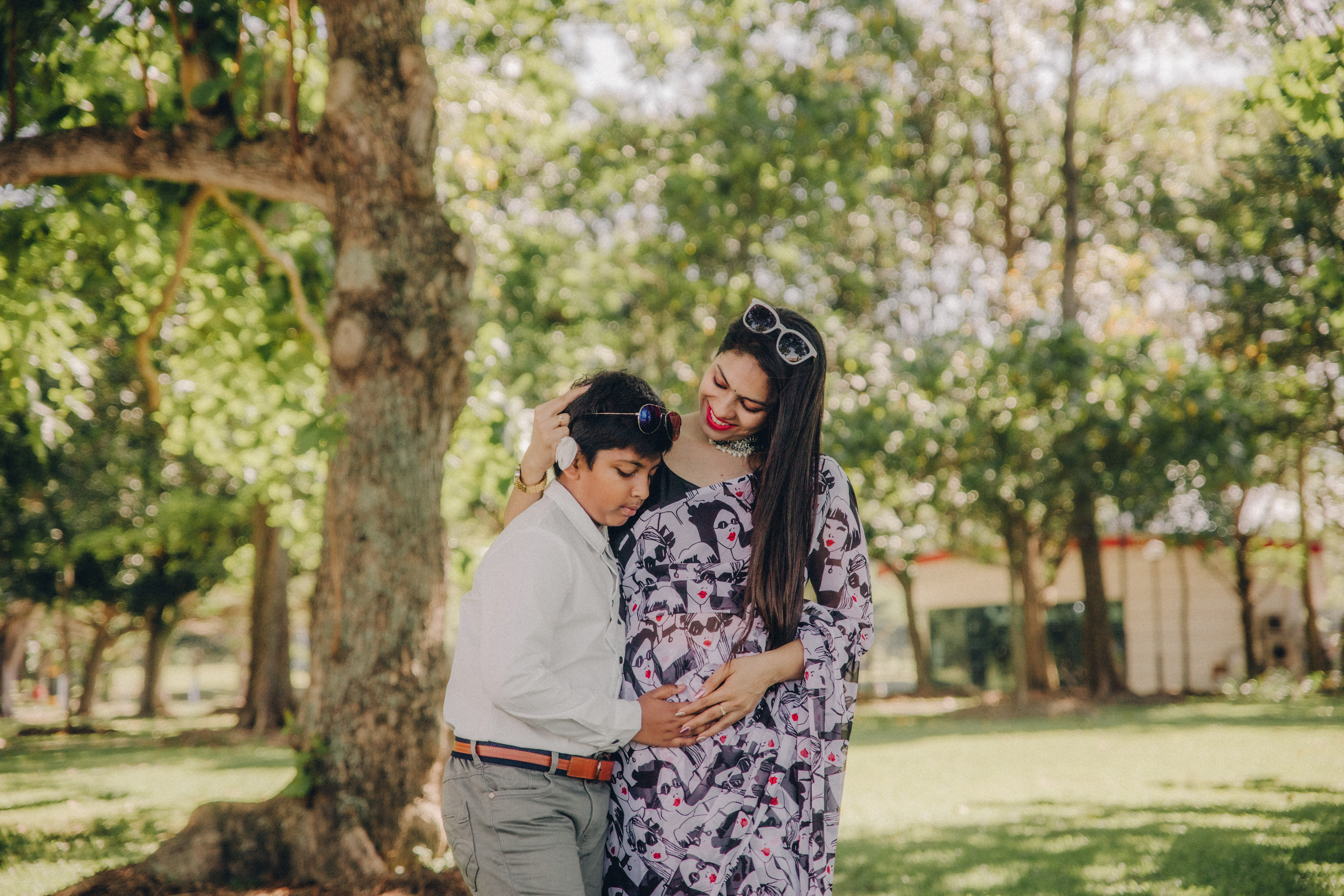 A proud brother-to-be resting his head gently on his mom's pregnant belly in a natural light setting