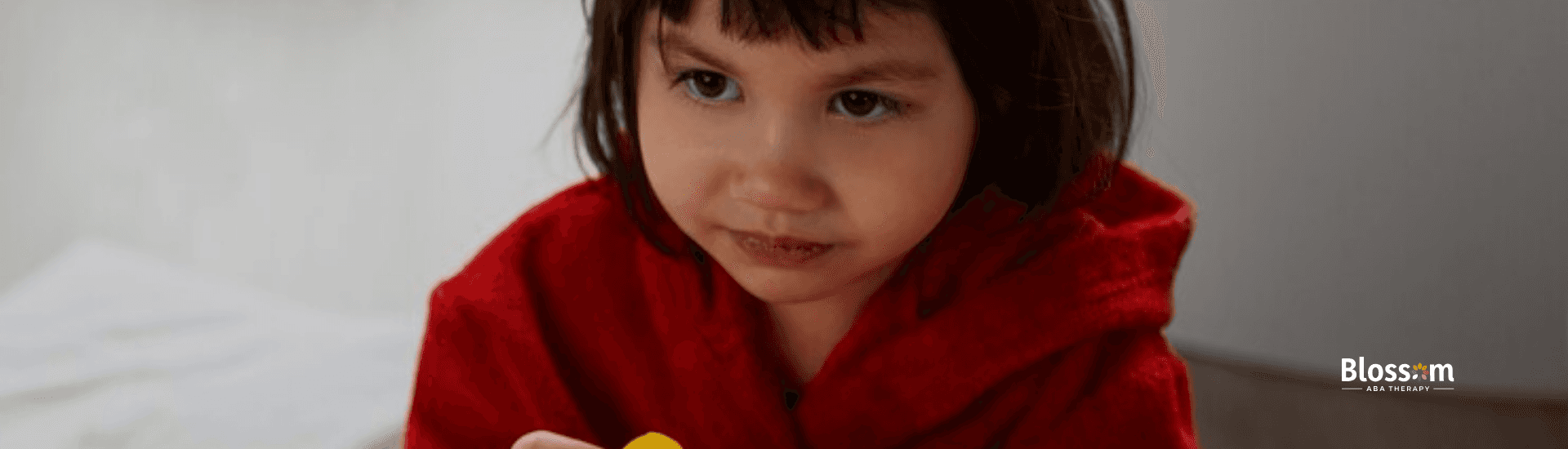 A little girl holding two toy ducks while smiling