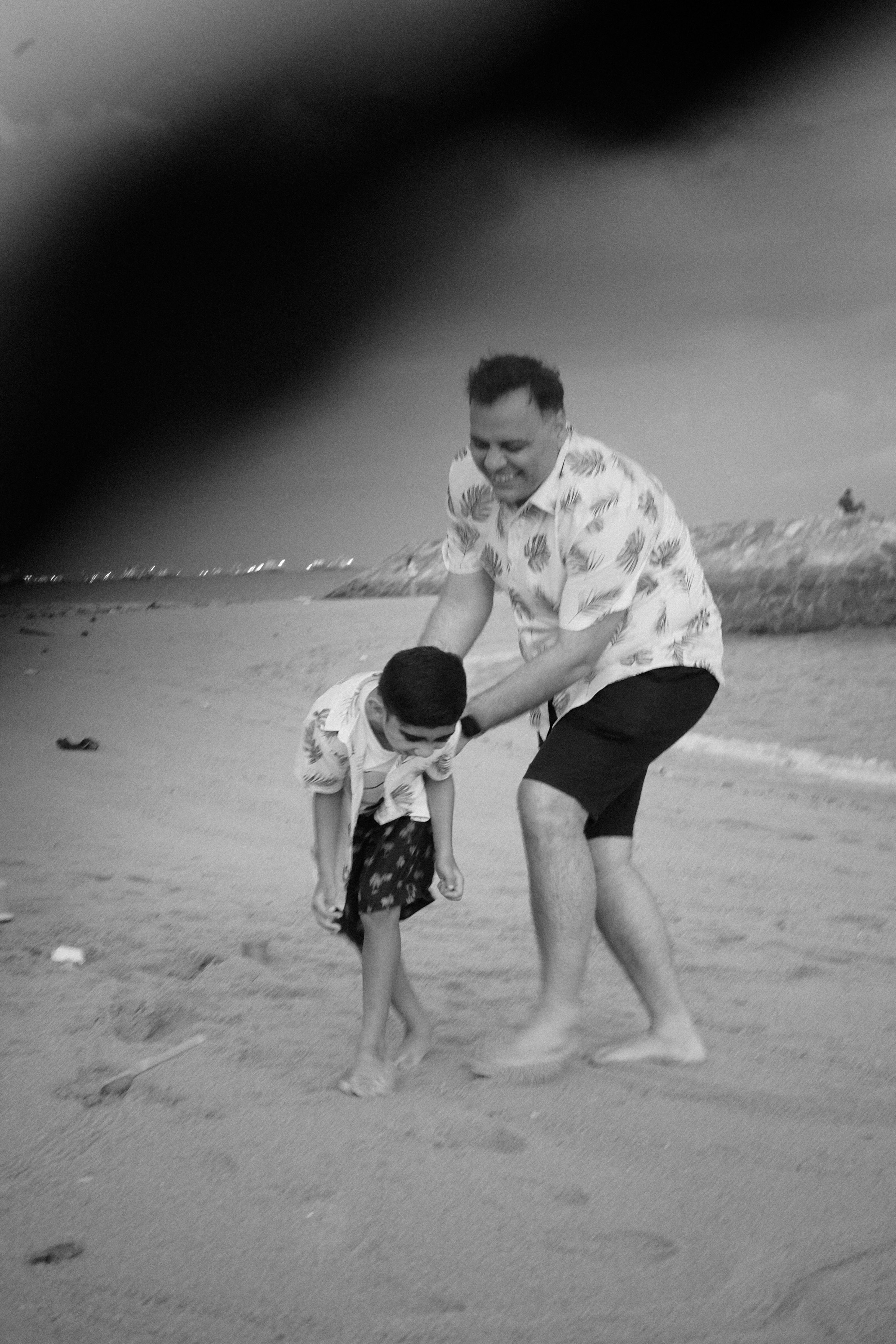 Father and son building a small sandcastle together on the East Coast Park shoreline.