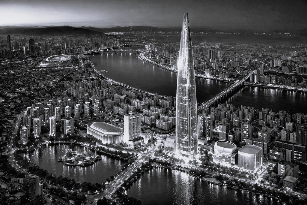 Modern red brick apartment or office building viewed from below against a blue sky, showcasing its geometric architecture with evenly spaced windows and balconies.