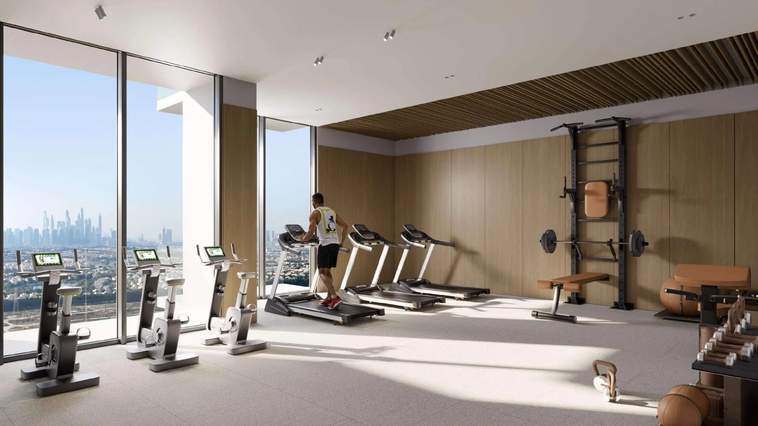 A gym room at Elaris Rise featuring large windows with a panoramic view of the city skyline.