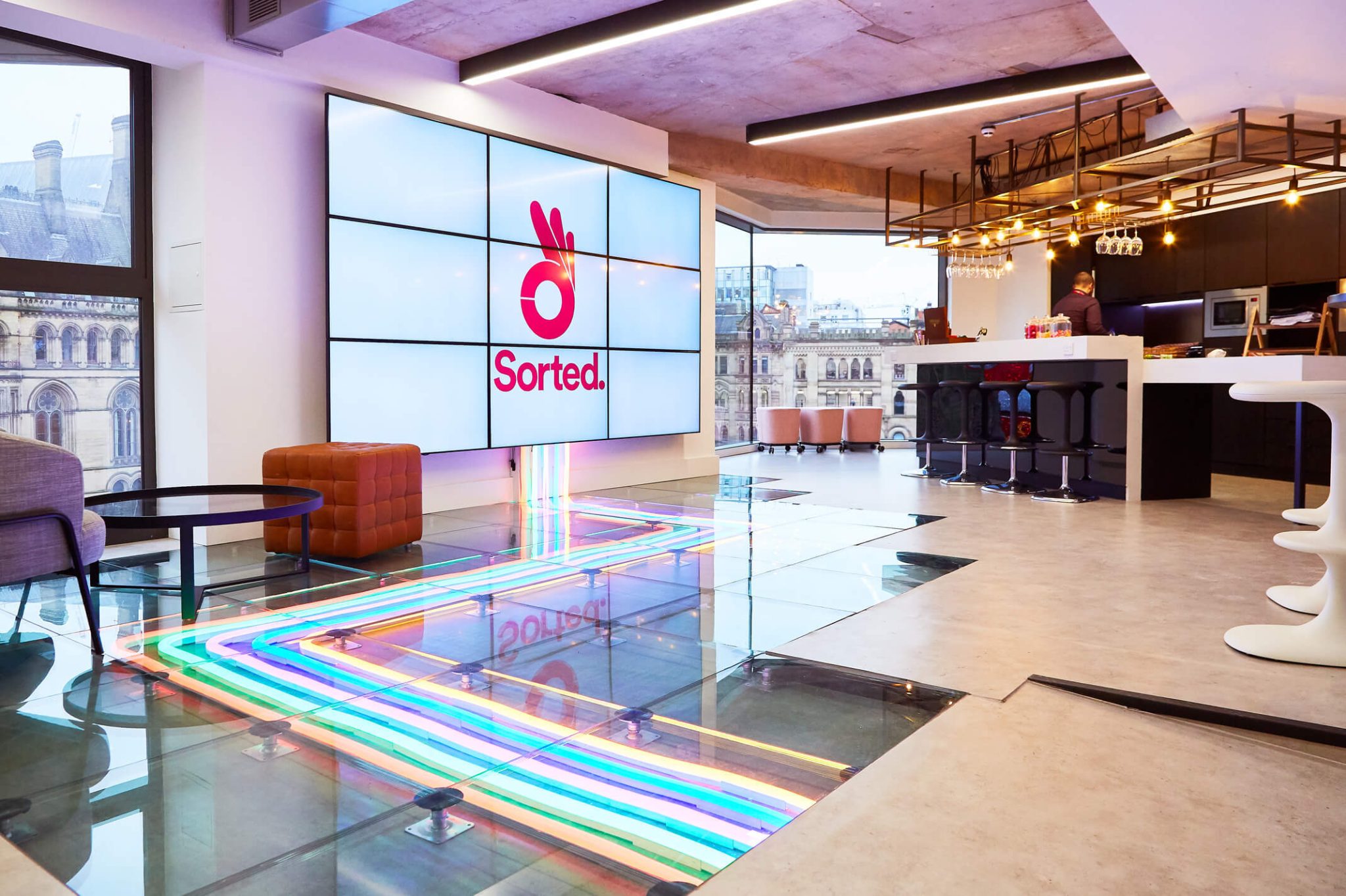 Modern Sorted office kitchen with neon-lit glass floor and large logo display