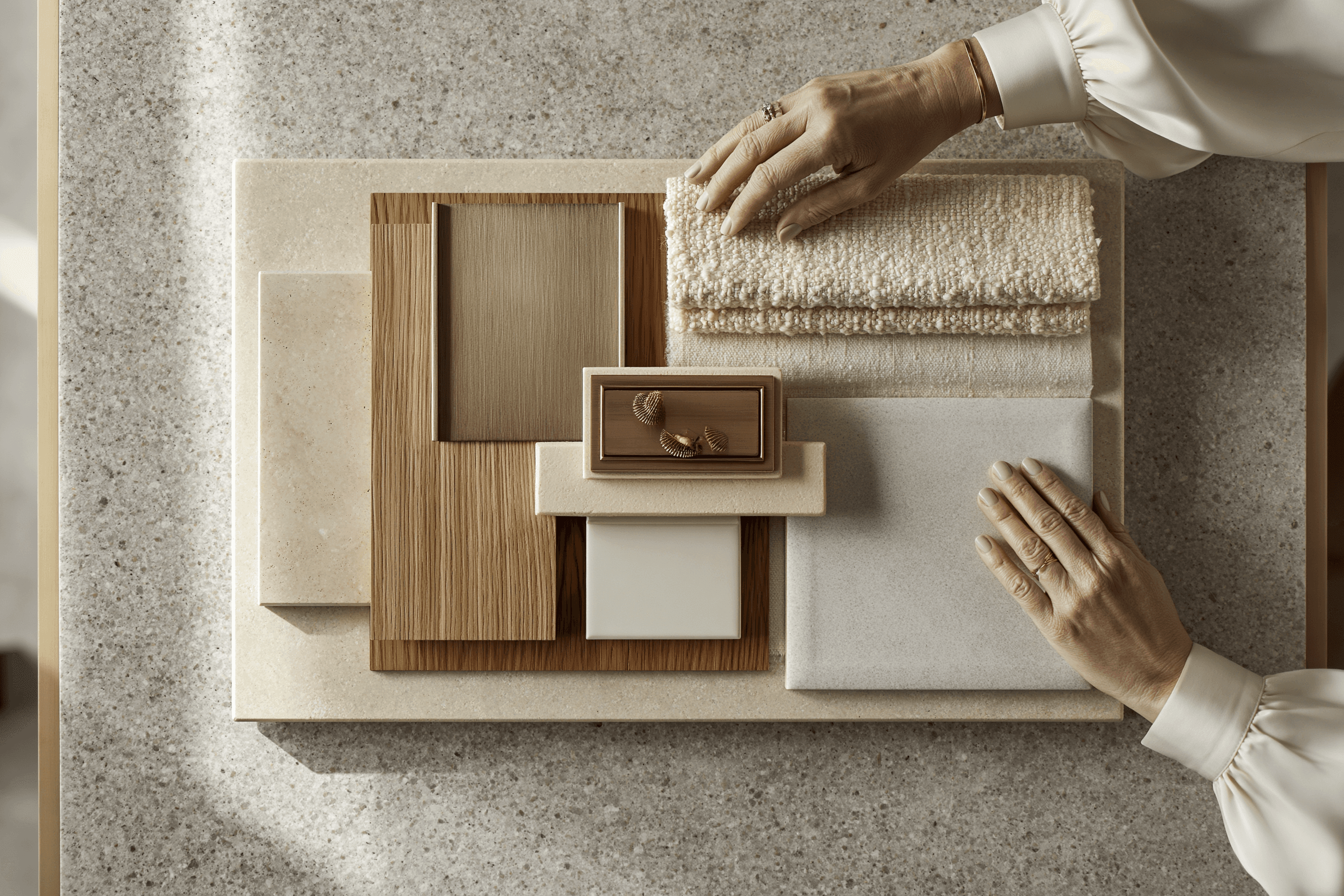 Material samples — concrete, timber, stone, brass — arranged in a precise row under warm raking light