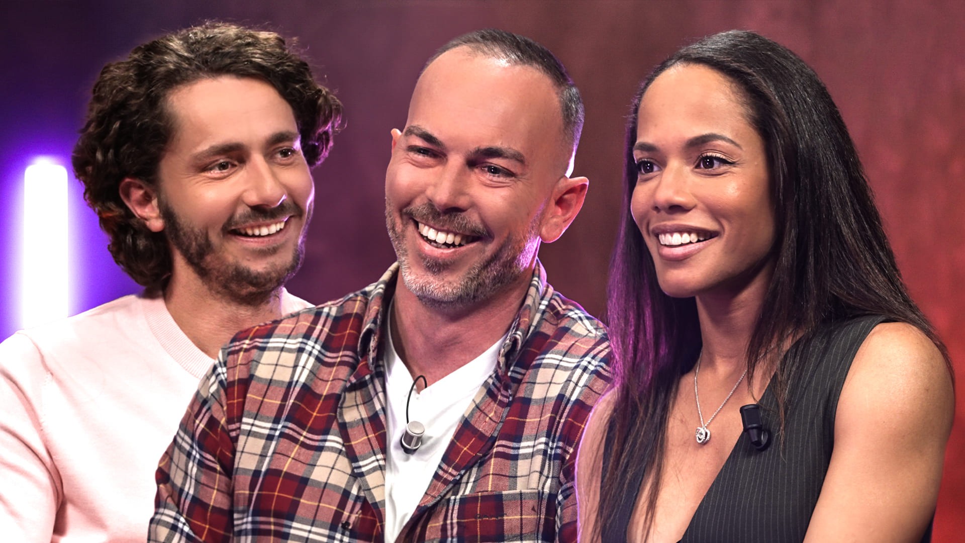 Miniature YouTube pour le média Legend, mettant en scène Guillaume Pley (à gauche, pull rose clair) interviewant un couple d'invités souriants (un homme barbu en chemise à carreaux et une femme en robe noire). Le trio est photographié en gros plan, avec un éclairage de studio intense et des lumières d'ambiance violettes/rouges en arrière-plan. Cette image illustre une interview sur un sujet social et de société sensible (couple libertin), soulignant le travail de Nux-Studio en direction artistique, graphisme de miniature (thumbnail) et production vidéo pour un contenu médiatique à fort engagement.