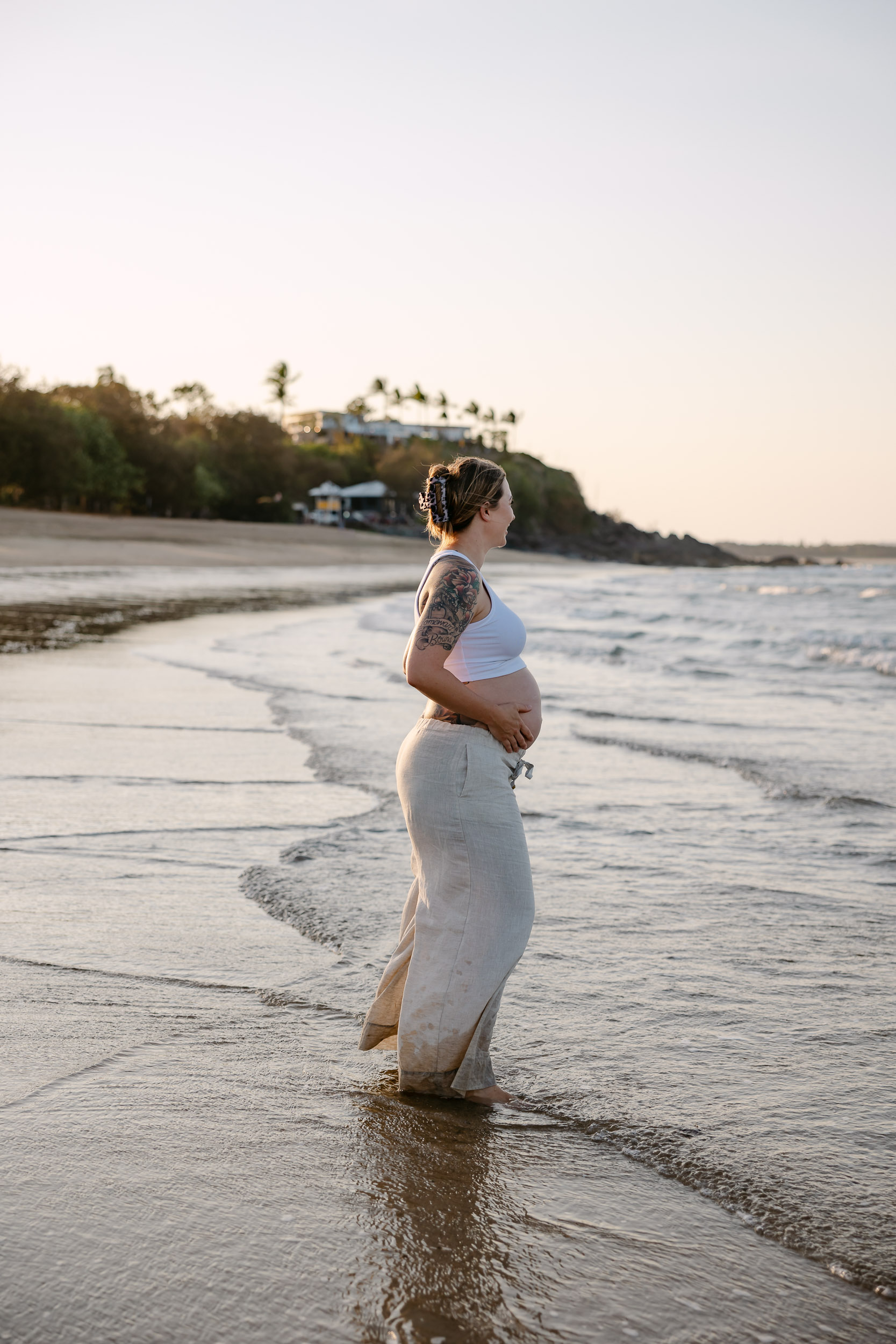 Pregnant woman walking on the shoreline at the beach