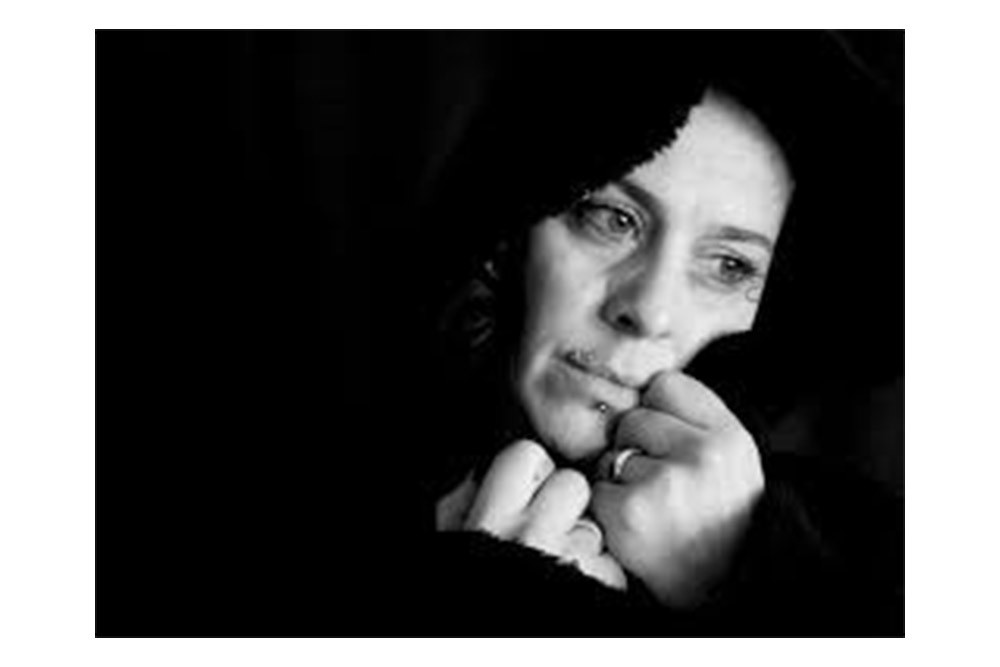 Black-and-white portrait of a worried middle-aged woman resting her chin on her hands