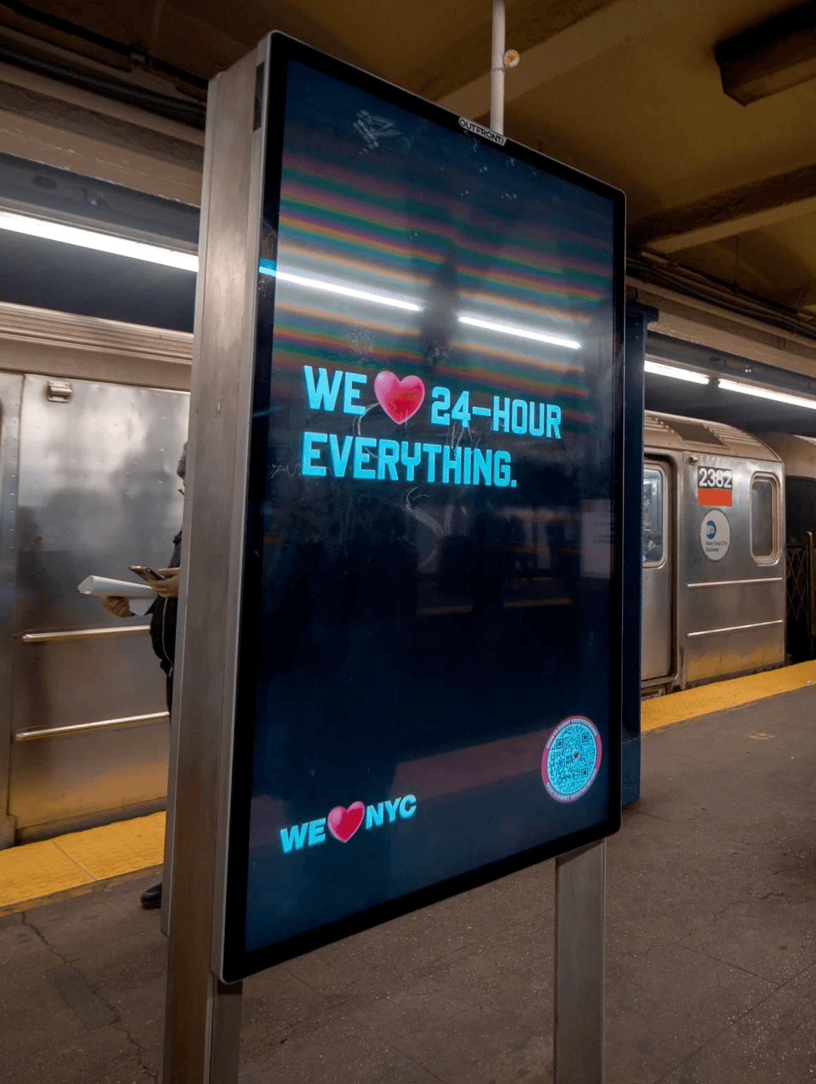 Digital sign on a subway platform that reads "We love 24-hour everything."