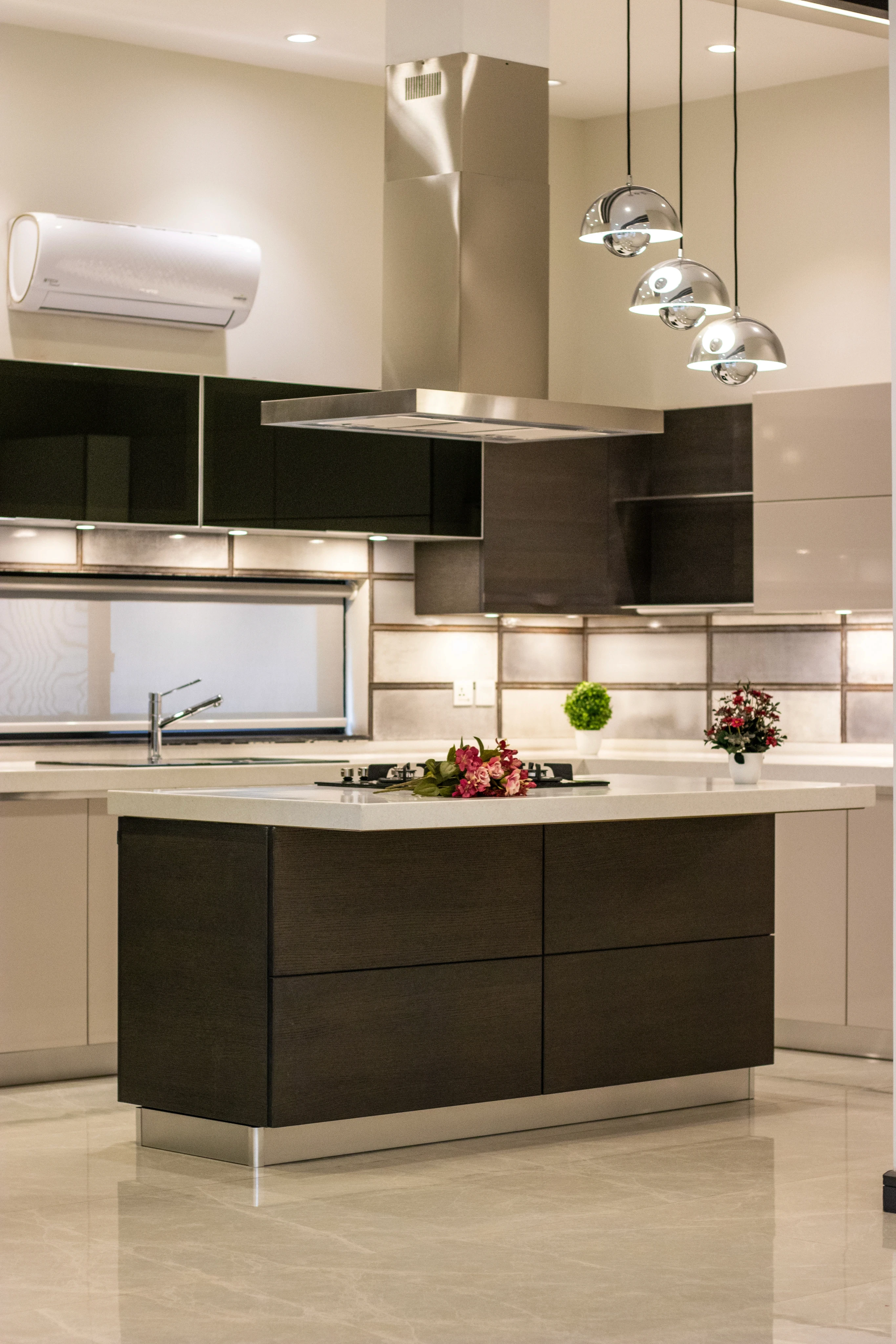 Modern kitchen with sleek dark cabinets, a central island topped with fruit, and stylish pendant lights. The ambiance is clean and contemporary.