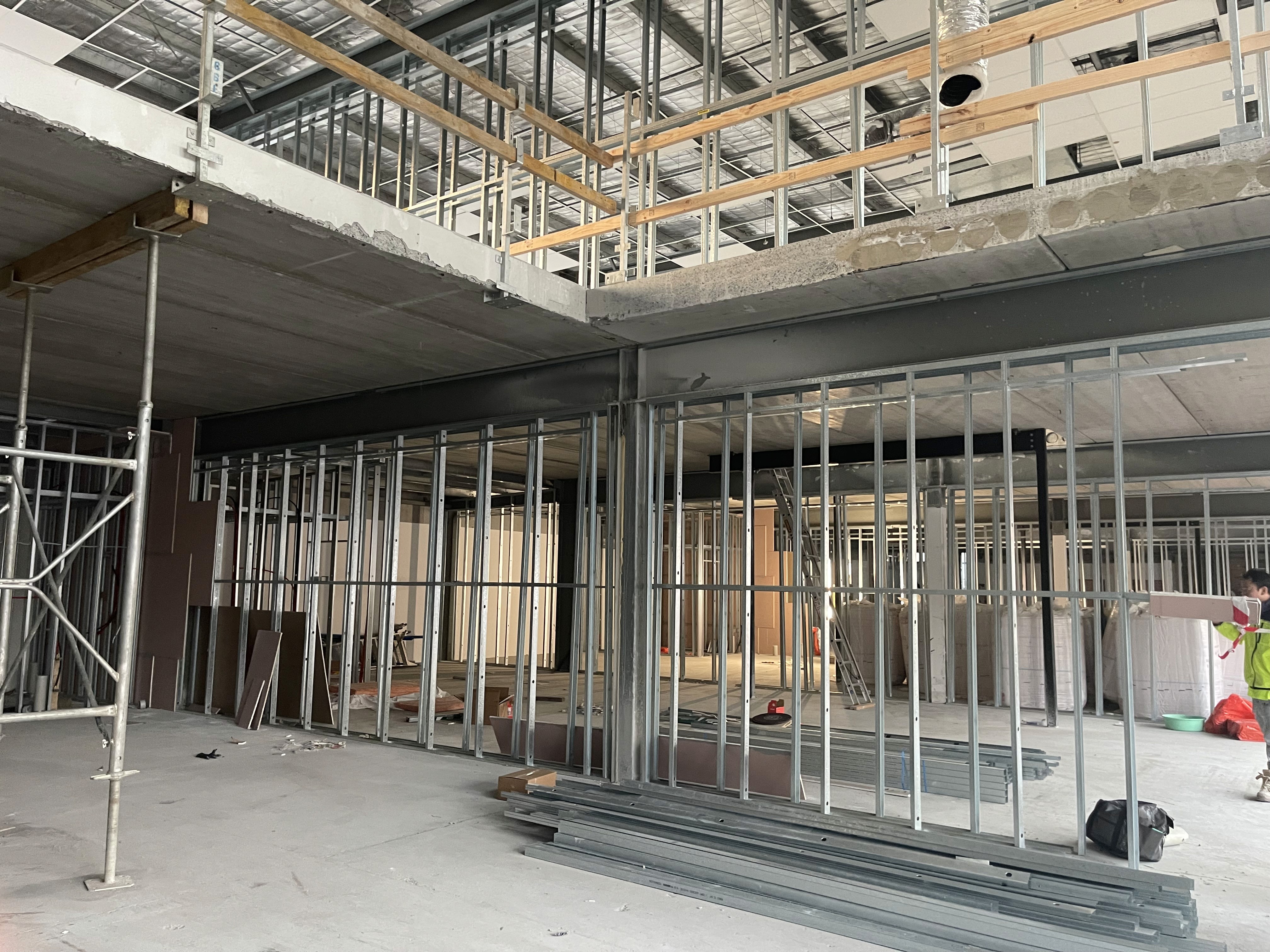 A serene outdoor lounge area with two chairs surrounded by lush greenery and natural light streaming in.