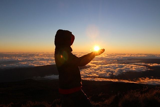 Silhouette of a person embracing the sunrise over Réunion Island, symbolizing hope and the métis spirit at the crossroads of Africa, Asia, and Europe.