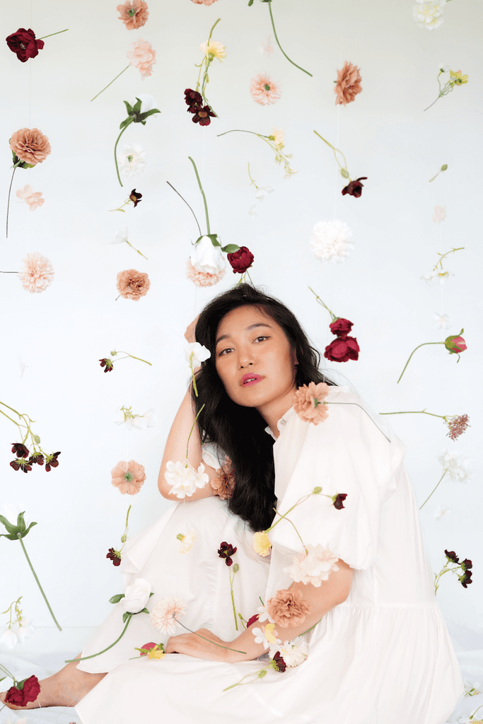 Person posing with flowers floating in the foreground