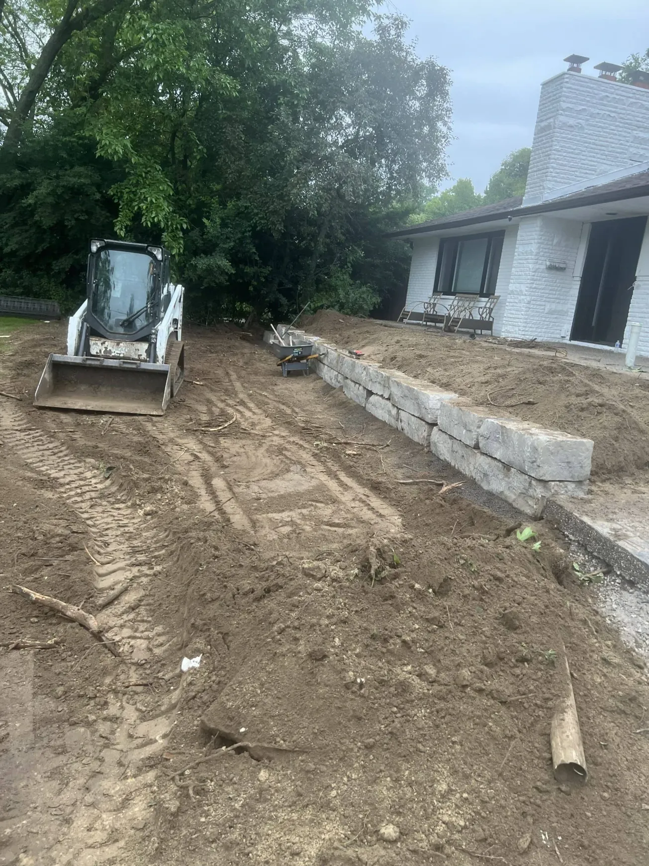 Falcons Landscaping excavating yard with Bobcat for property leveling.
