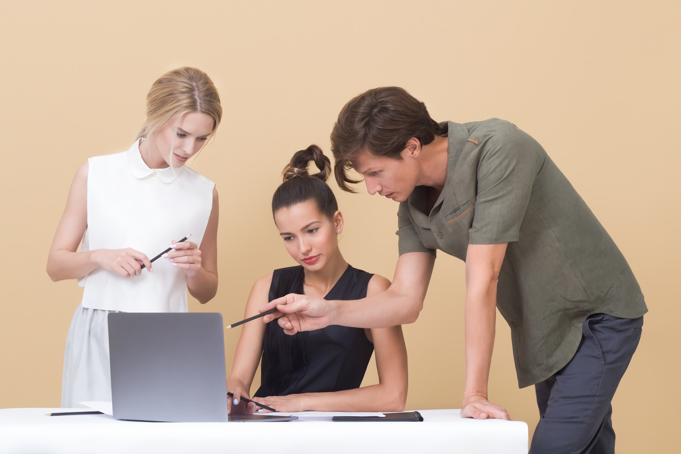 Two colleagues review work together on a laptop.