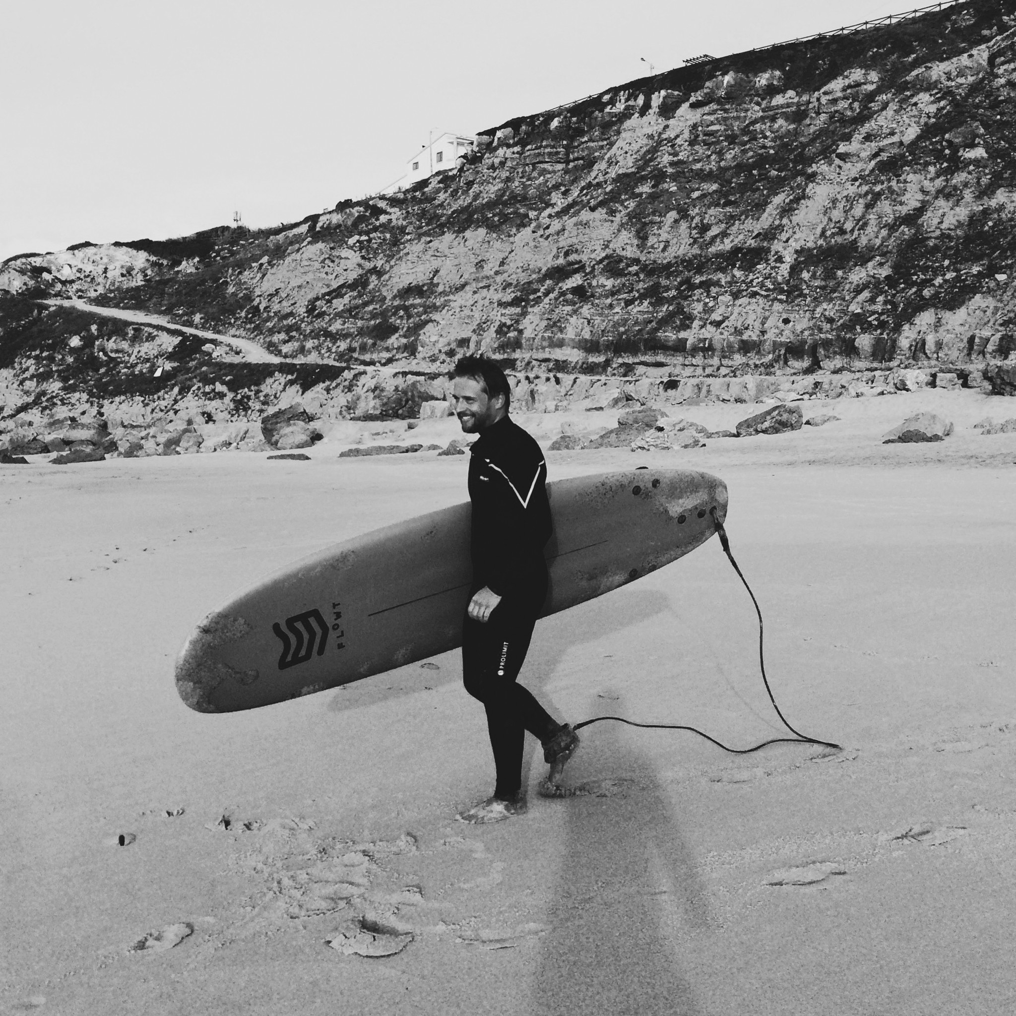 Patrick Meyer mit seinem Surfbrett am Strand.