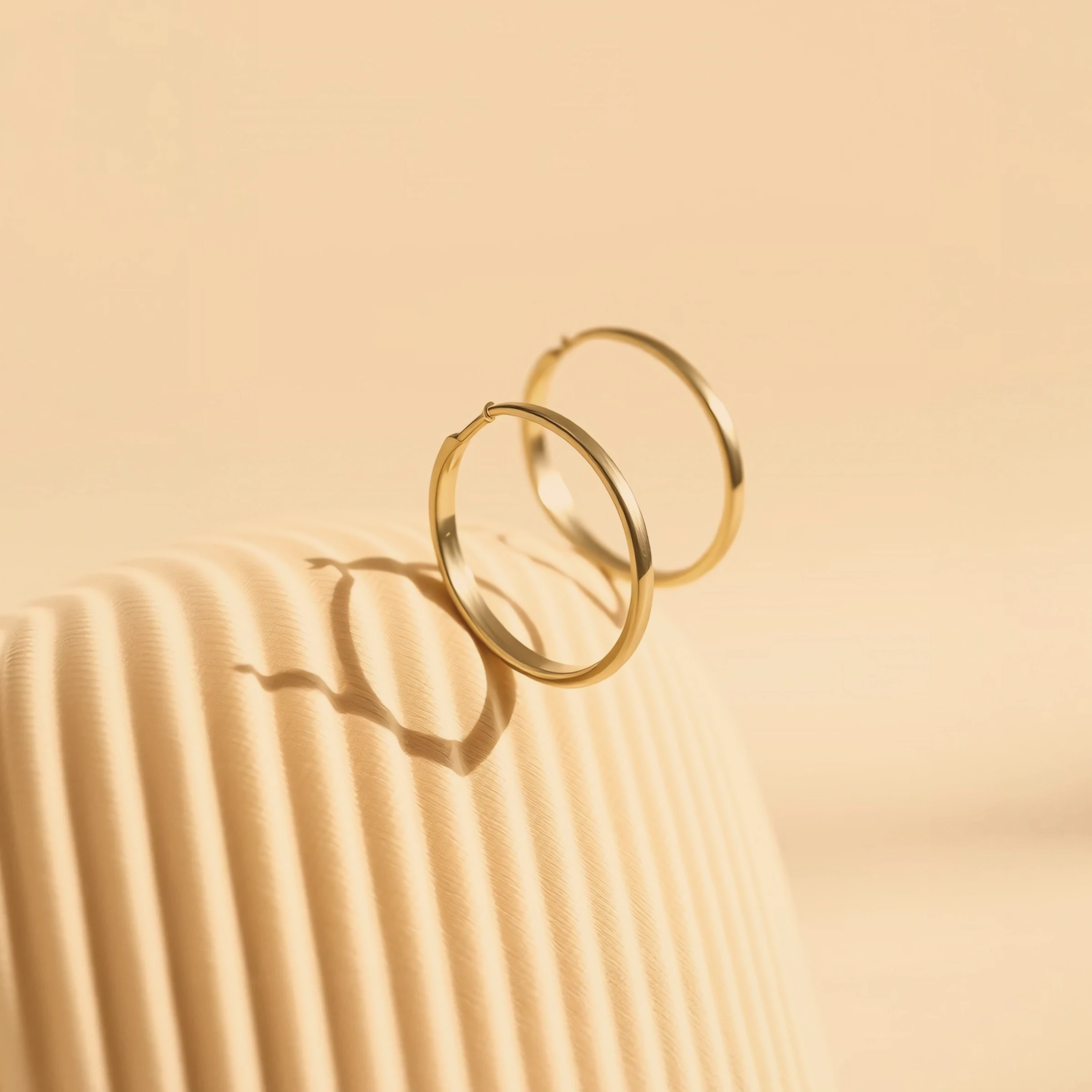 Gold Hoop Earrings on Beige Background