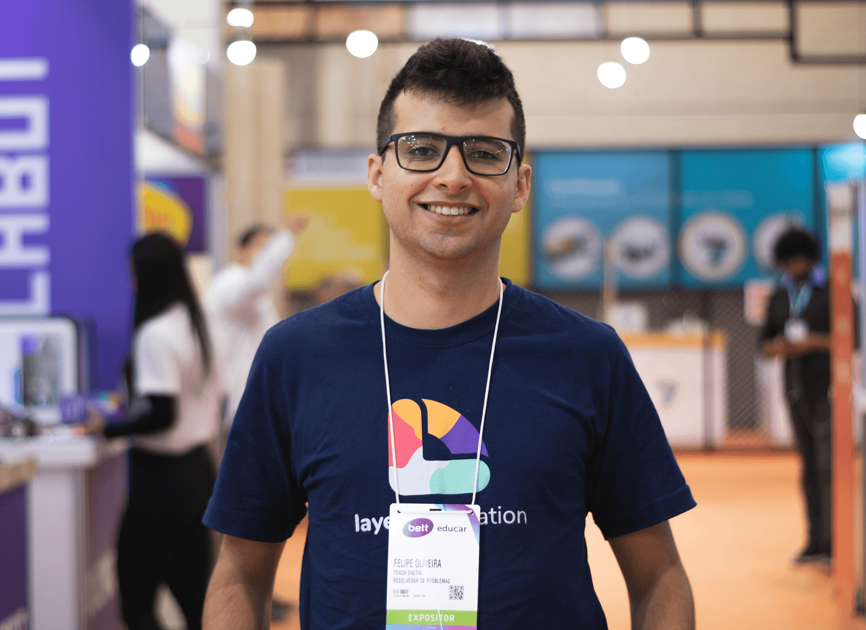 Smiling man with glasses and ID badge