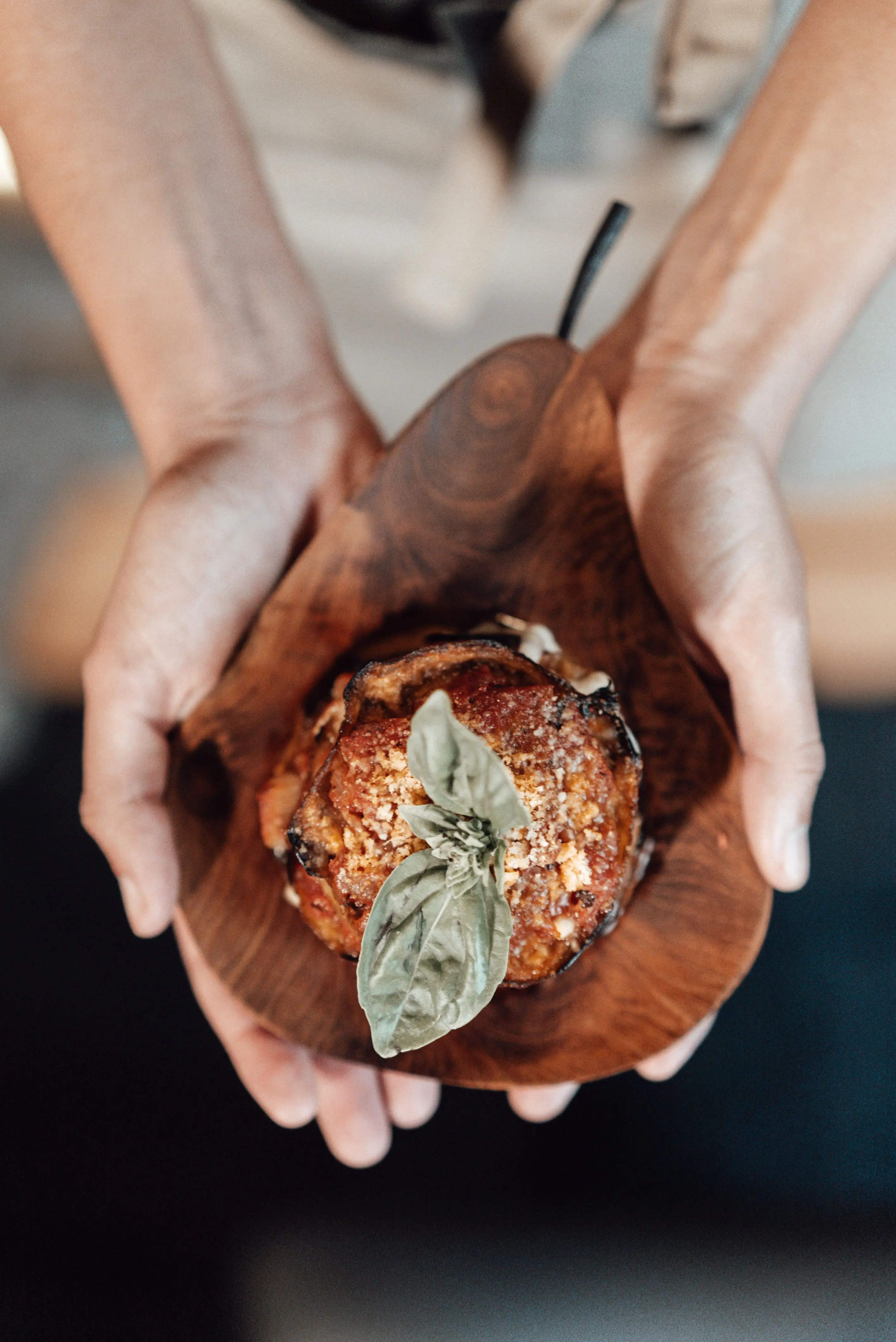 Hands holding a prepared dish during service