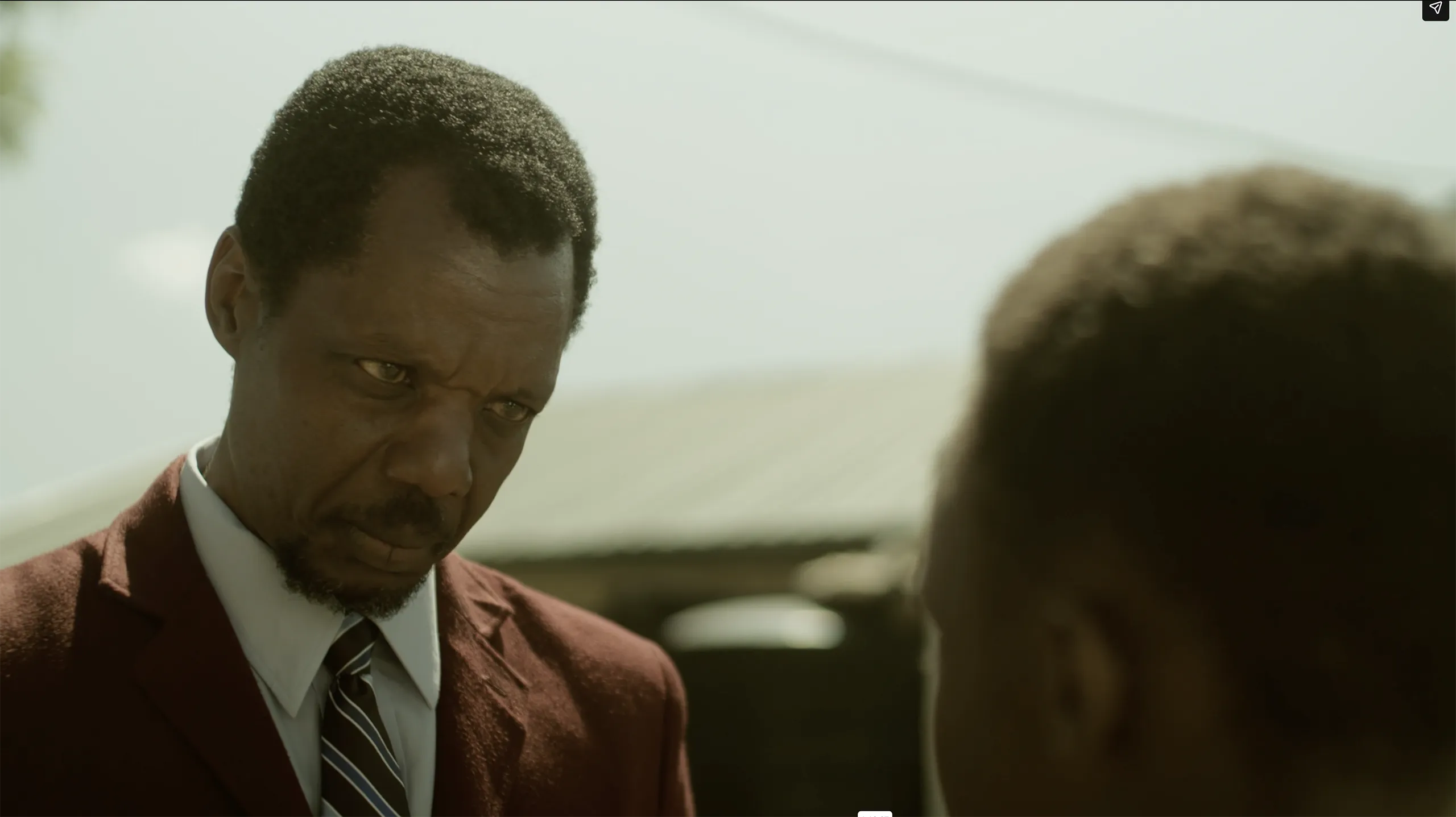 A dramatic cinematic shot of two men in a intense conversation with warm earth tone color grading.