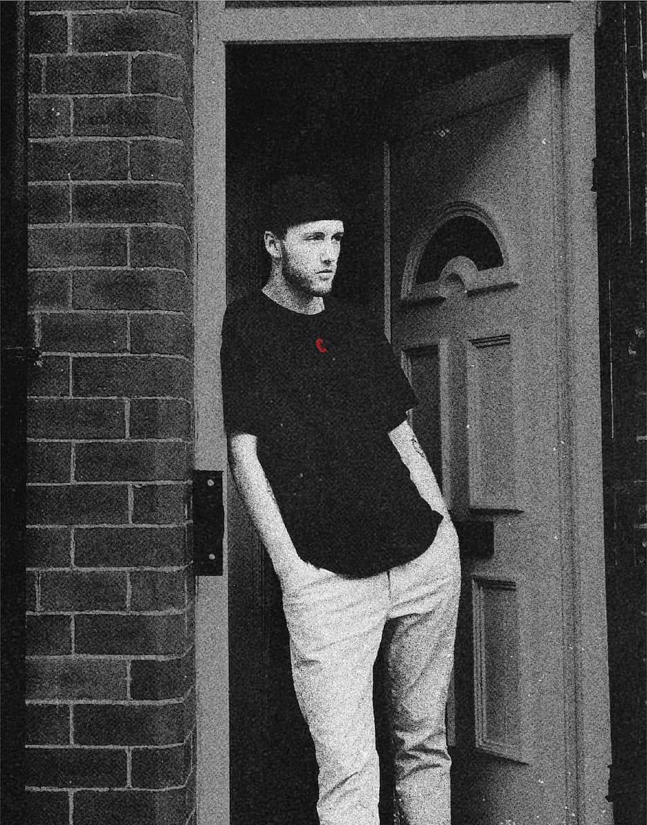 Model in doorway wearing creep t-shirt minimal red mark.