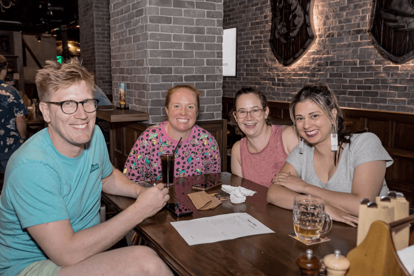 four friends in casual clothes posing for tavern trivia