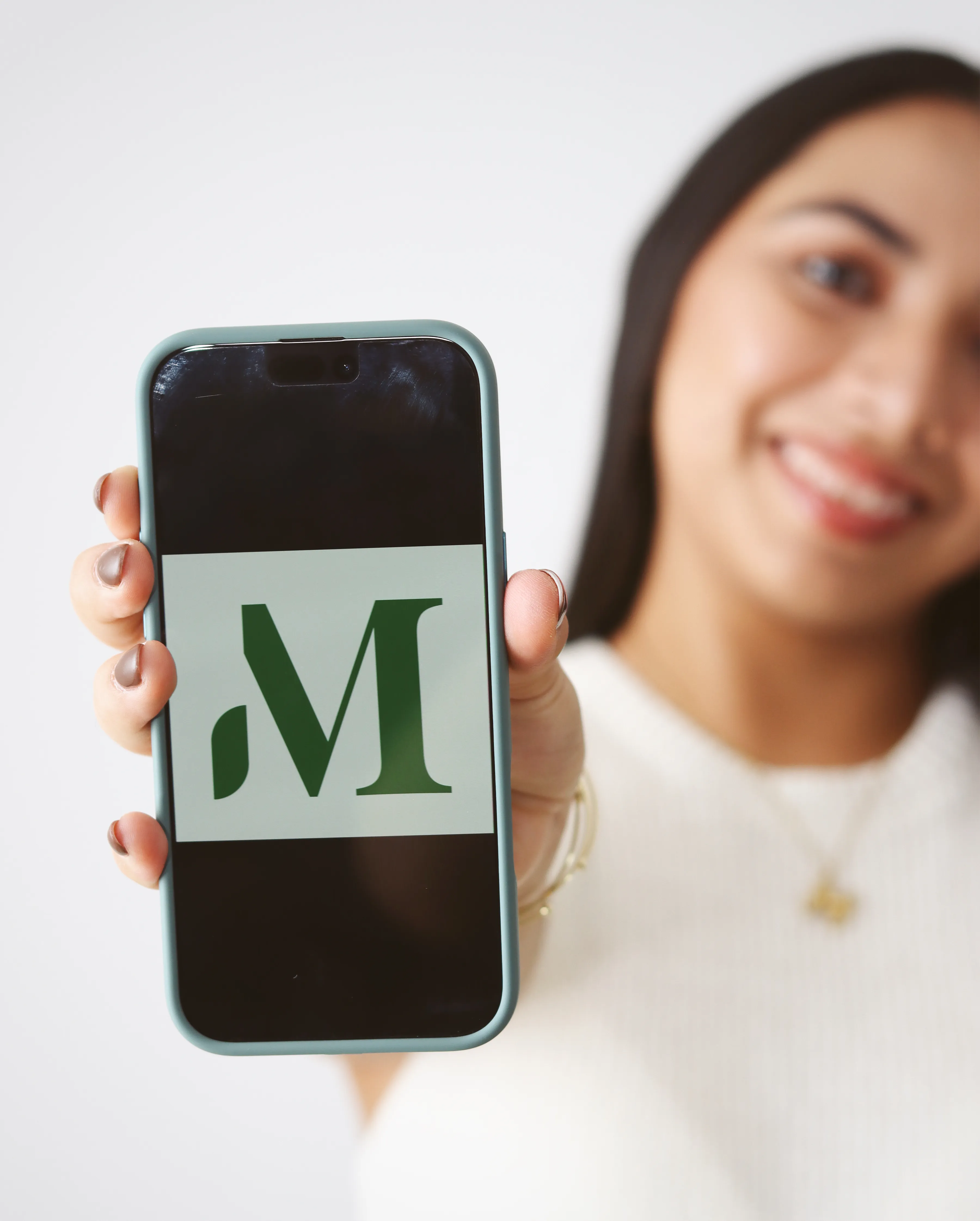 Mujer sosteniendo celular con logo verde de Wellness with Mel.