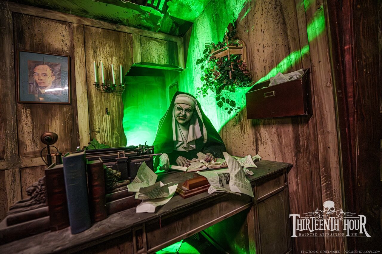Scare actor dressed as a nun seated at a cluttered desk