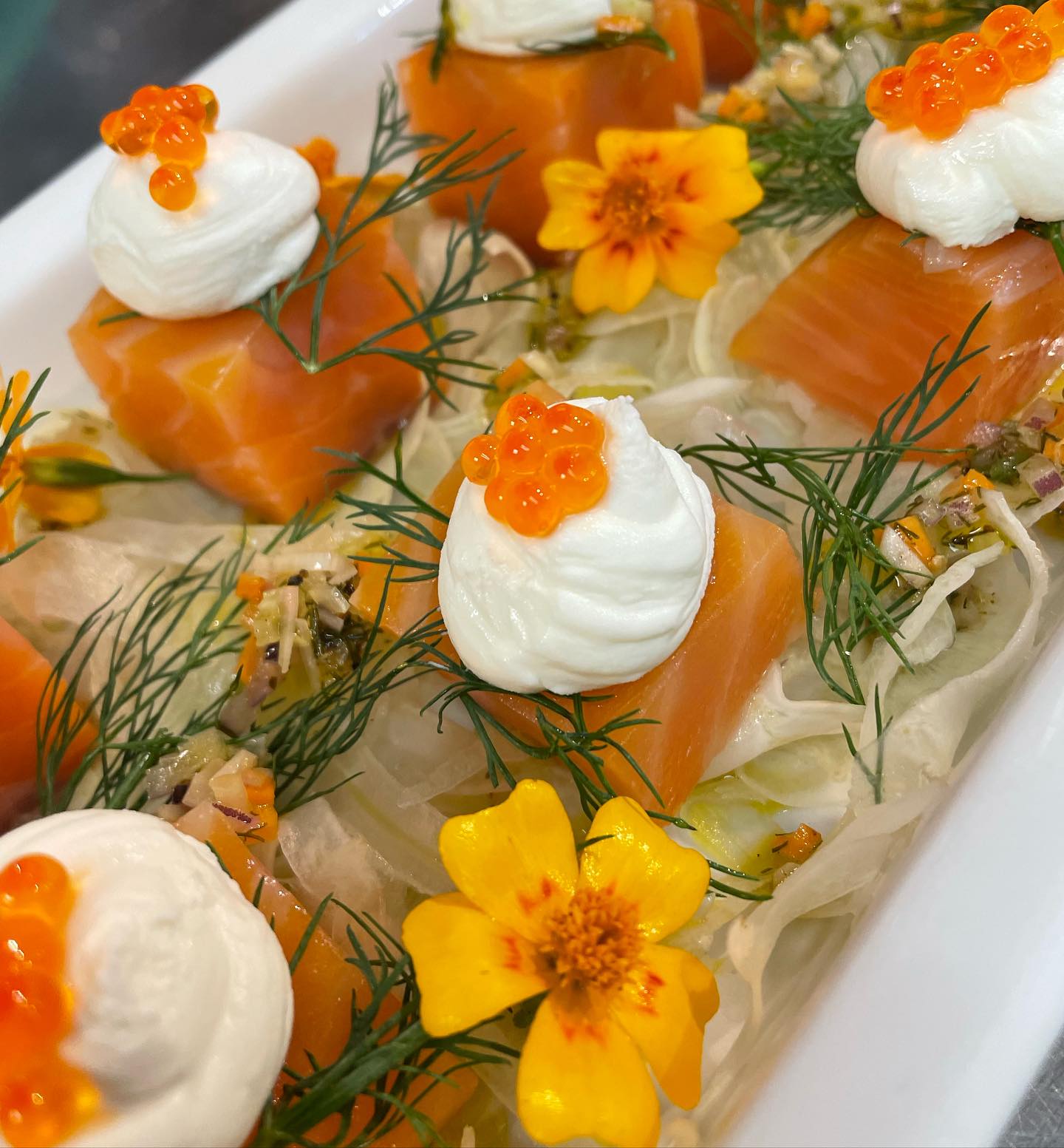 Vakkert anrett laks toppet med dill, rogn og spiselige blomster