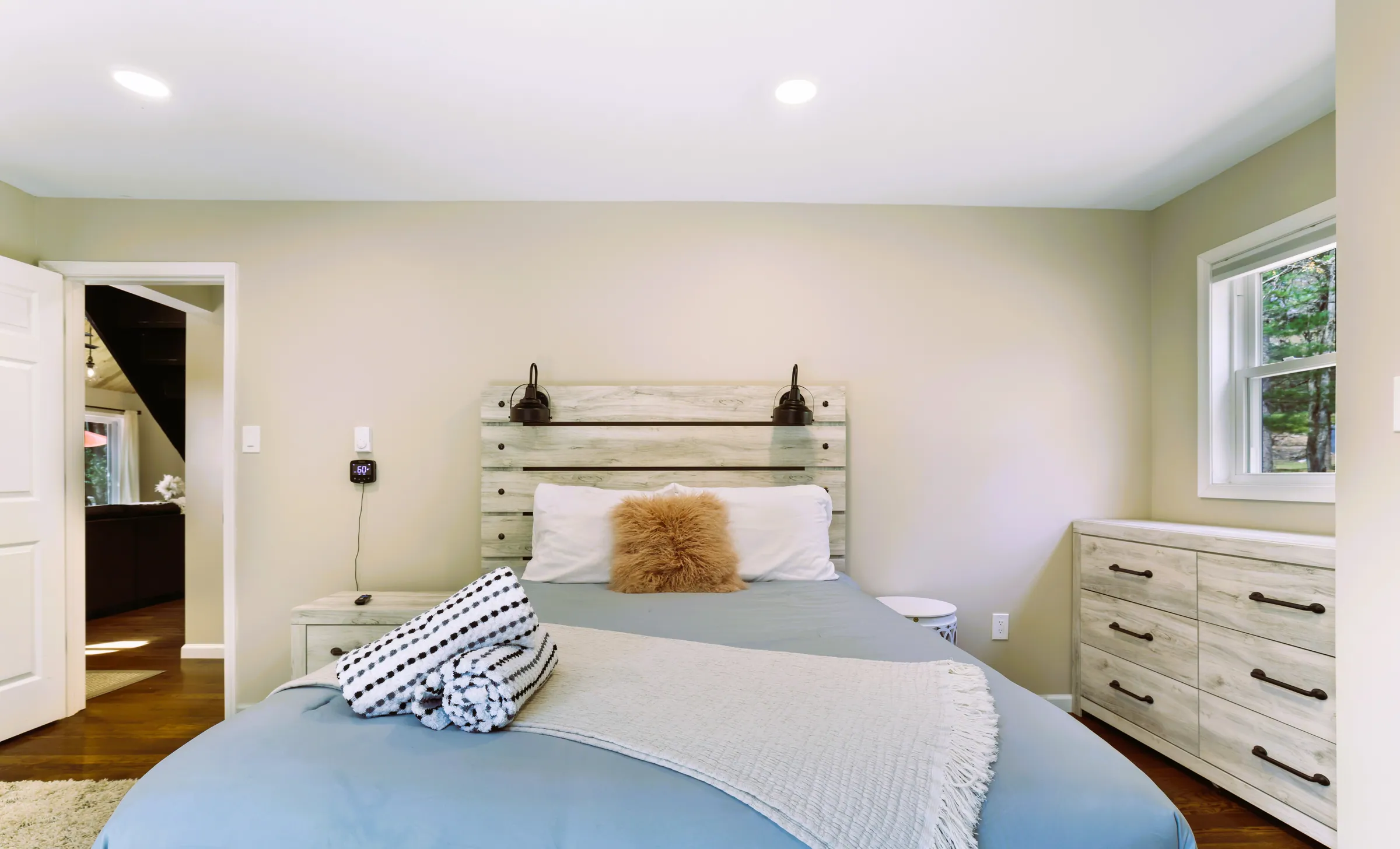 Queen bedroom with whitewashed headboard, blue bedding and dresser at Divine on Lupine