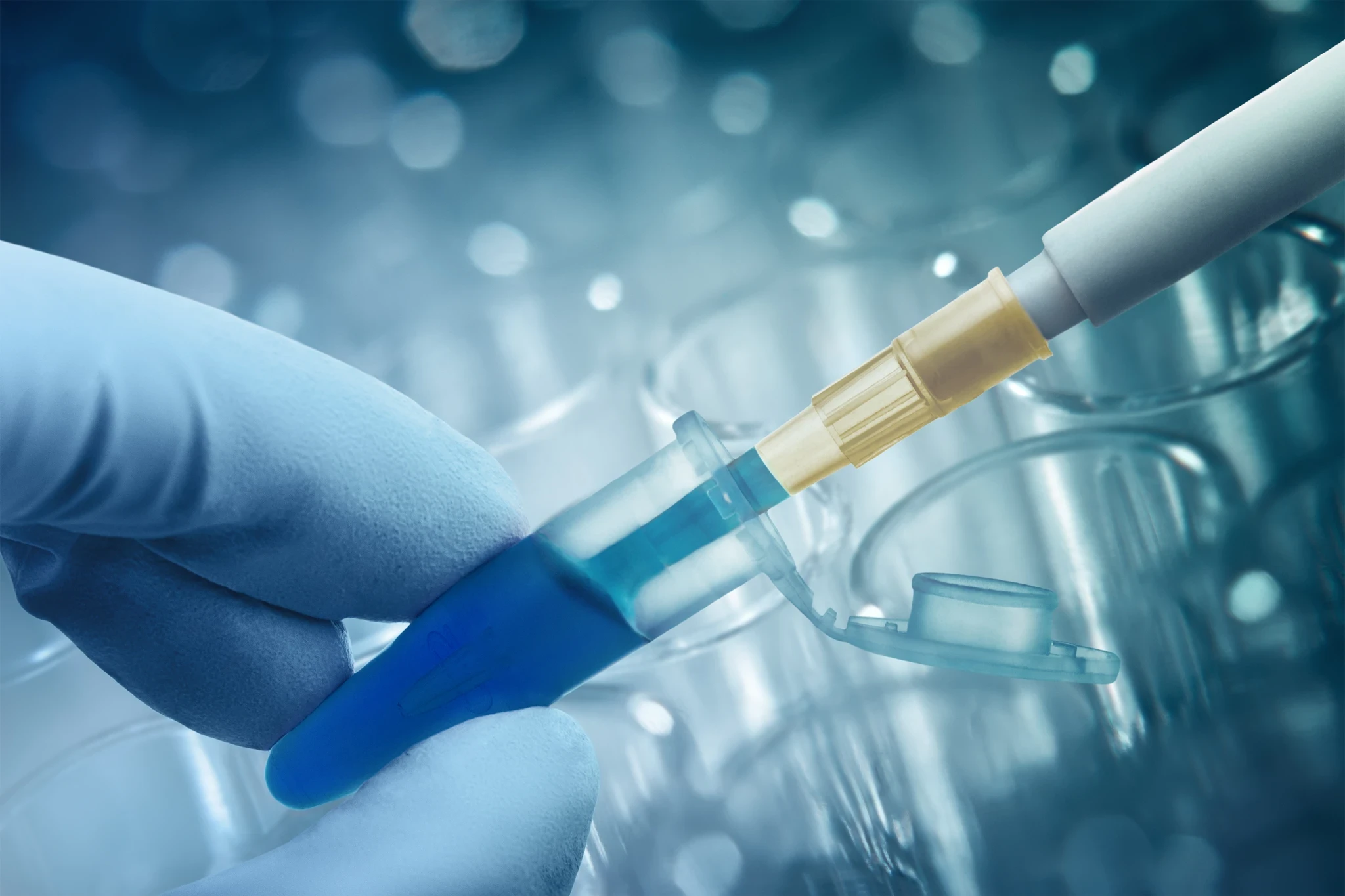 Gloved hand holding a blue-tinted diagnostic test cassette while a probe dispenses liquid.