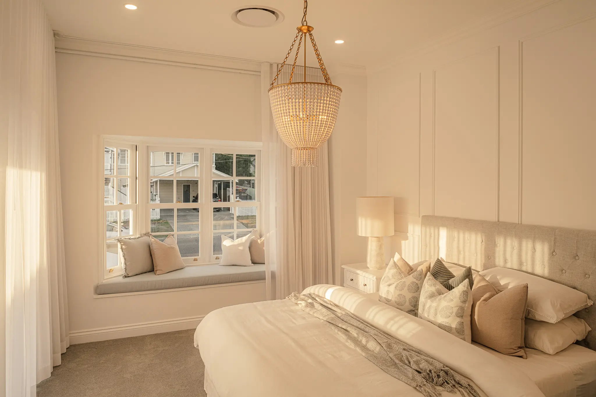 A luxurious master suite with window seat and chandelier
