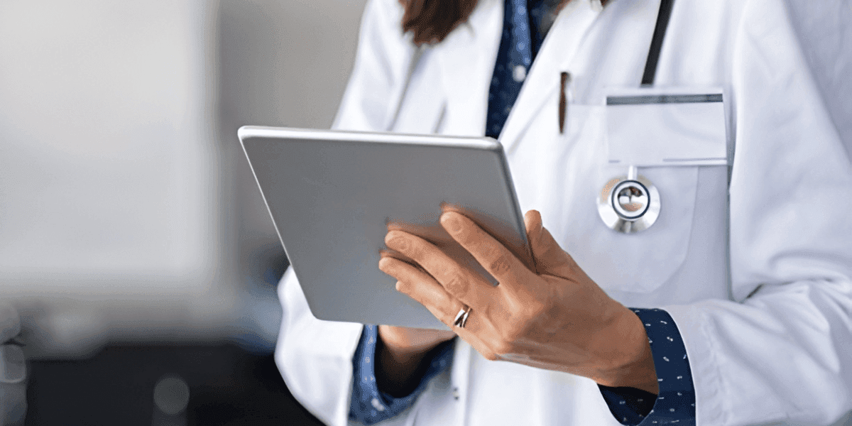 Female doctor in a white coat reviewing patient notes on a tablet while looking out over the city at Venus Women's Health.