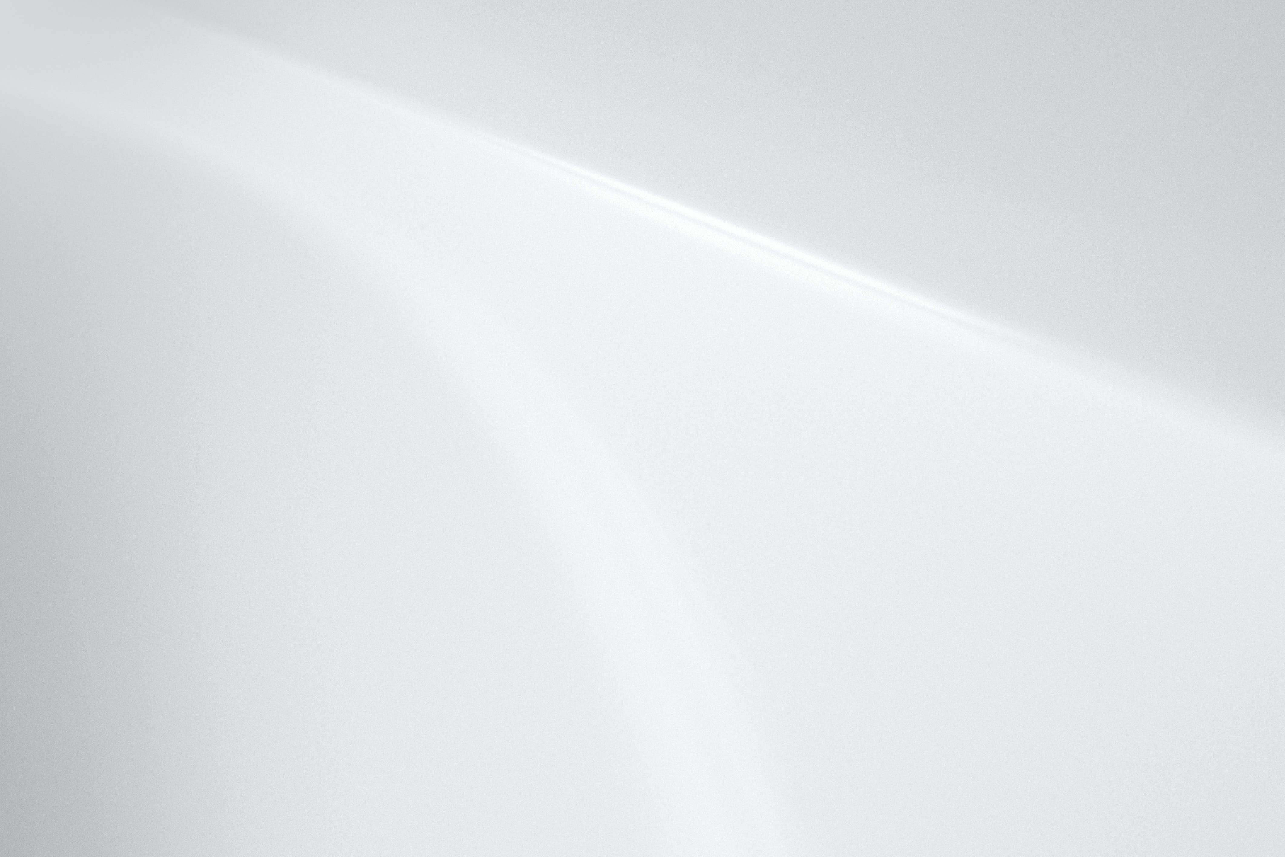 A smooth, curved white surface with soft gradients and lighting.