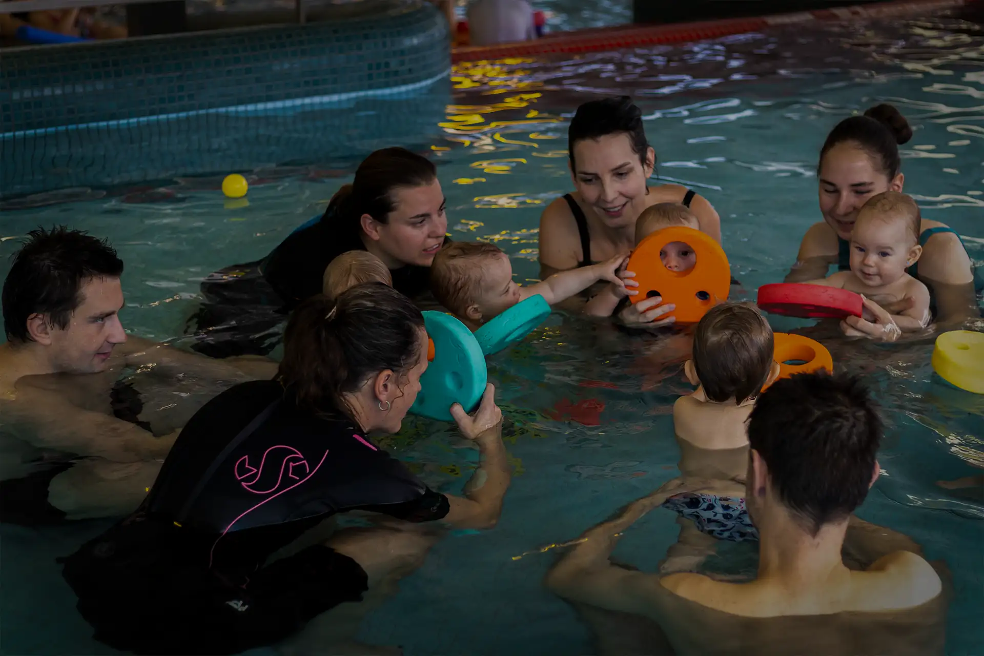 rodice a deti hrajici si ve vode v kruhu v bazenu