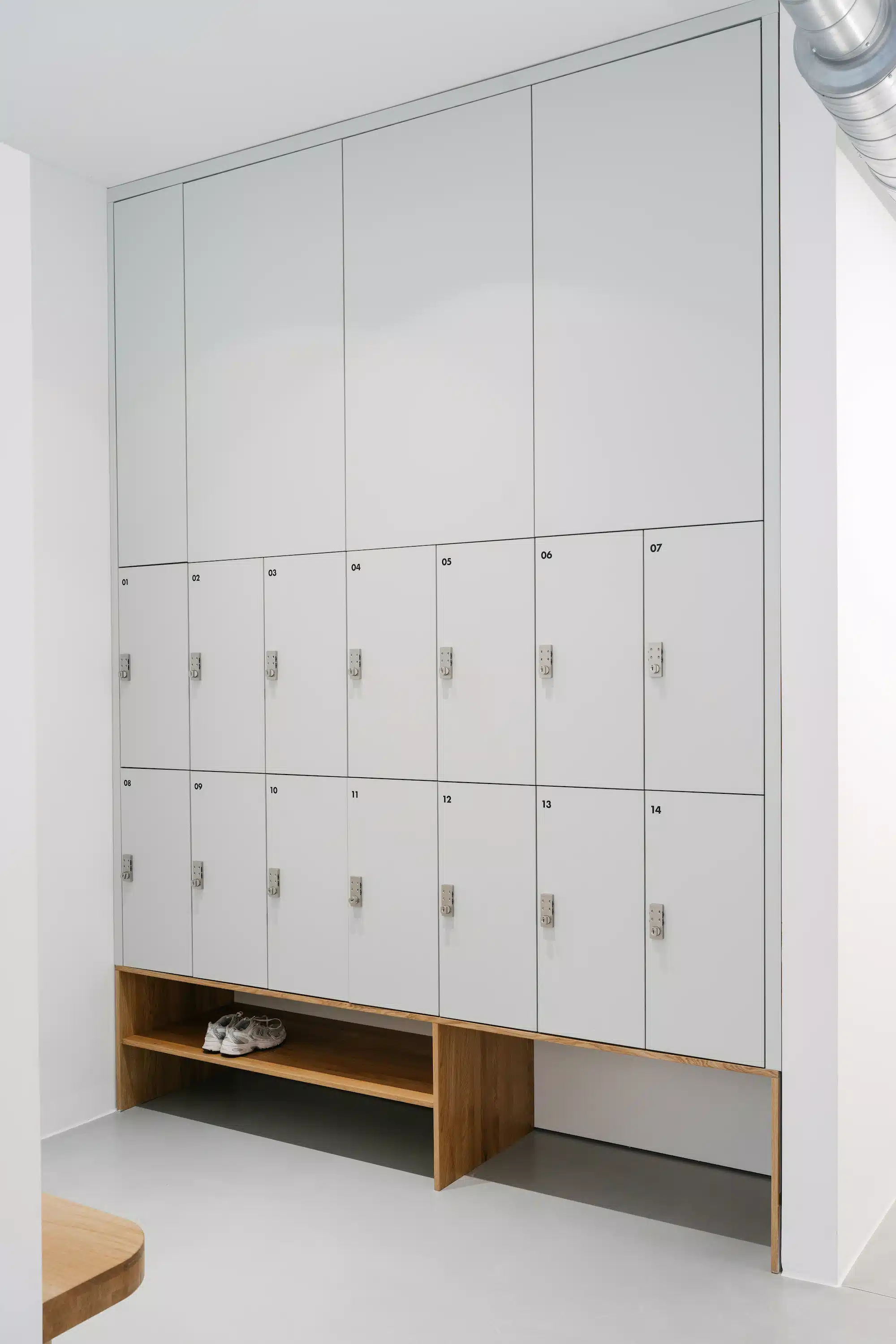 Reforma – minimalist changing area with white locker wall and wooden bench