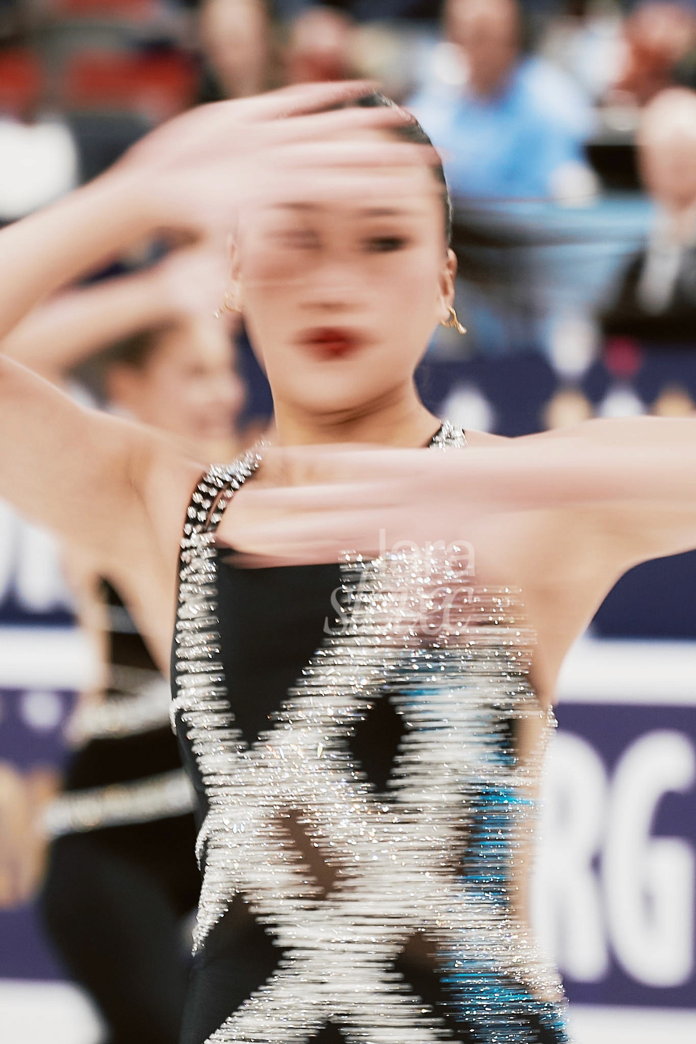 Portrait in Bewegungsunschärfe einer Synchroneiskunstläuferin. Die Hände vor dem Gesicht. Nur das rechte Auge und der Mund sind zu erkennen. Team Unity. ISU Synchronized Skating Championships 2026 in Salzburg. Fotografiert von Lara Slevec.