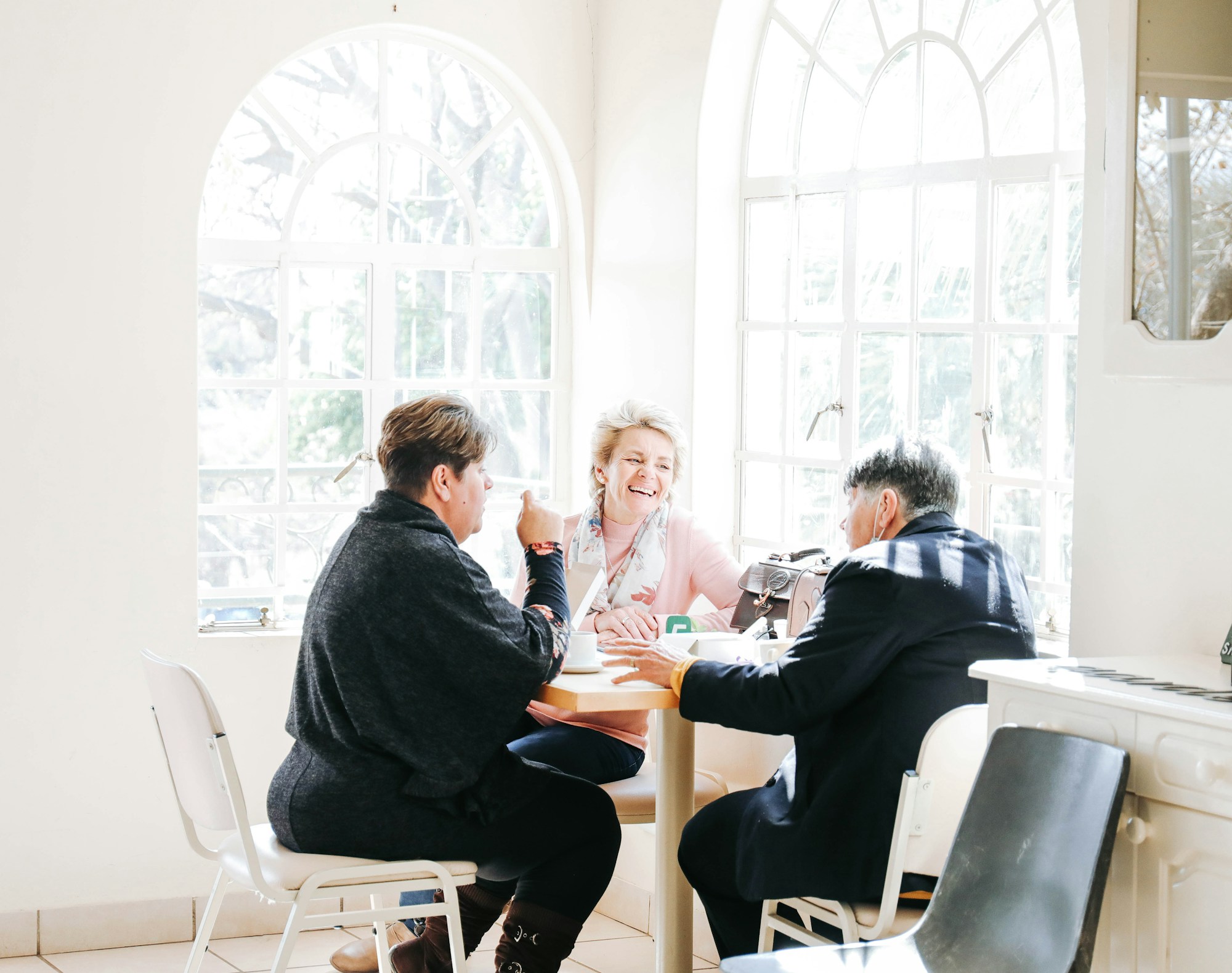 Three clients and an advisor talking at a table beneath tall arched windows