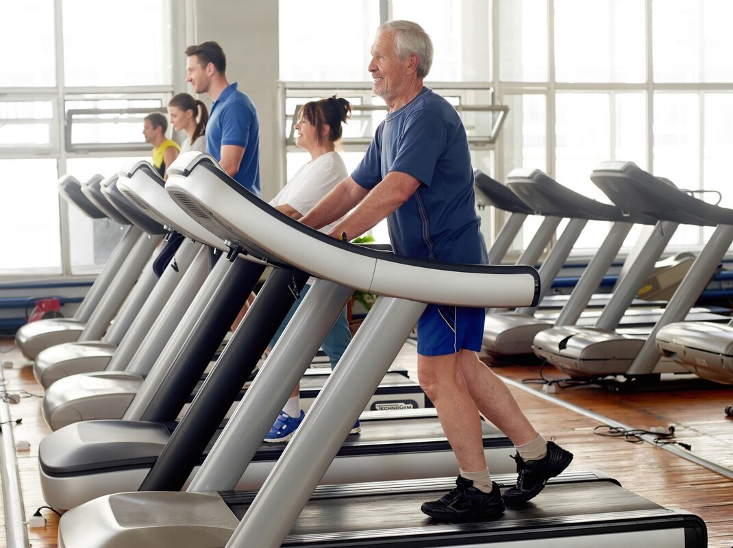 older man with joining issues at the gym doing a beginner weight loss treadmill workout by walking slowly