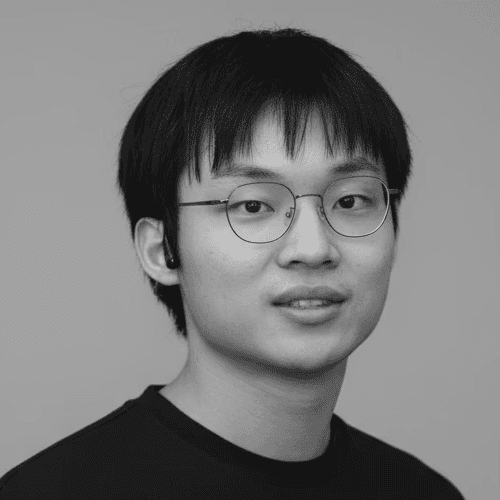 Portrait of a man with short dark hair and a trimmed beard, dressed in a dark shirt, on a simple background.