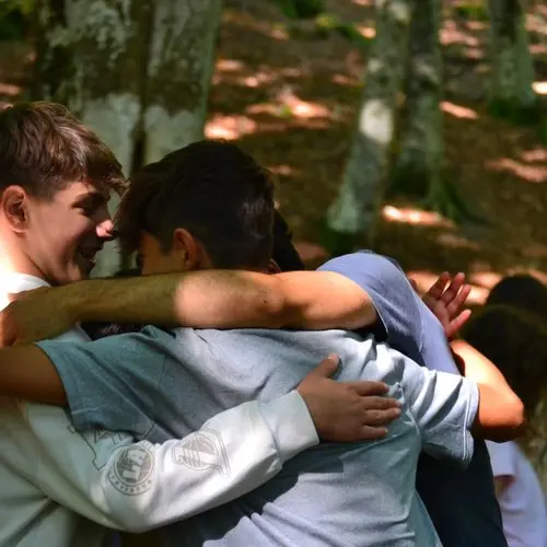 Ragazzi che si abbracciano durante un campo estivo consapevole in natura in Toscana sviluppando relazione e fiducia