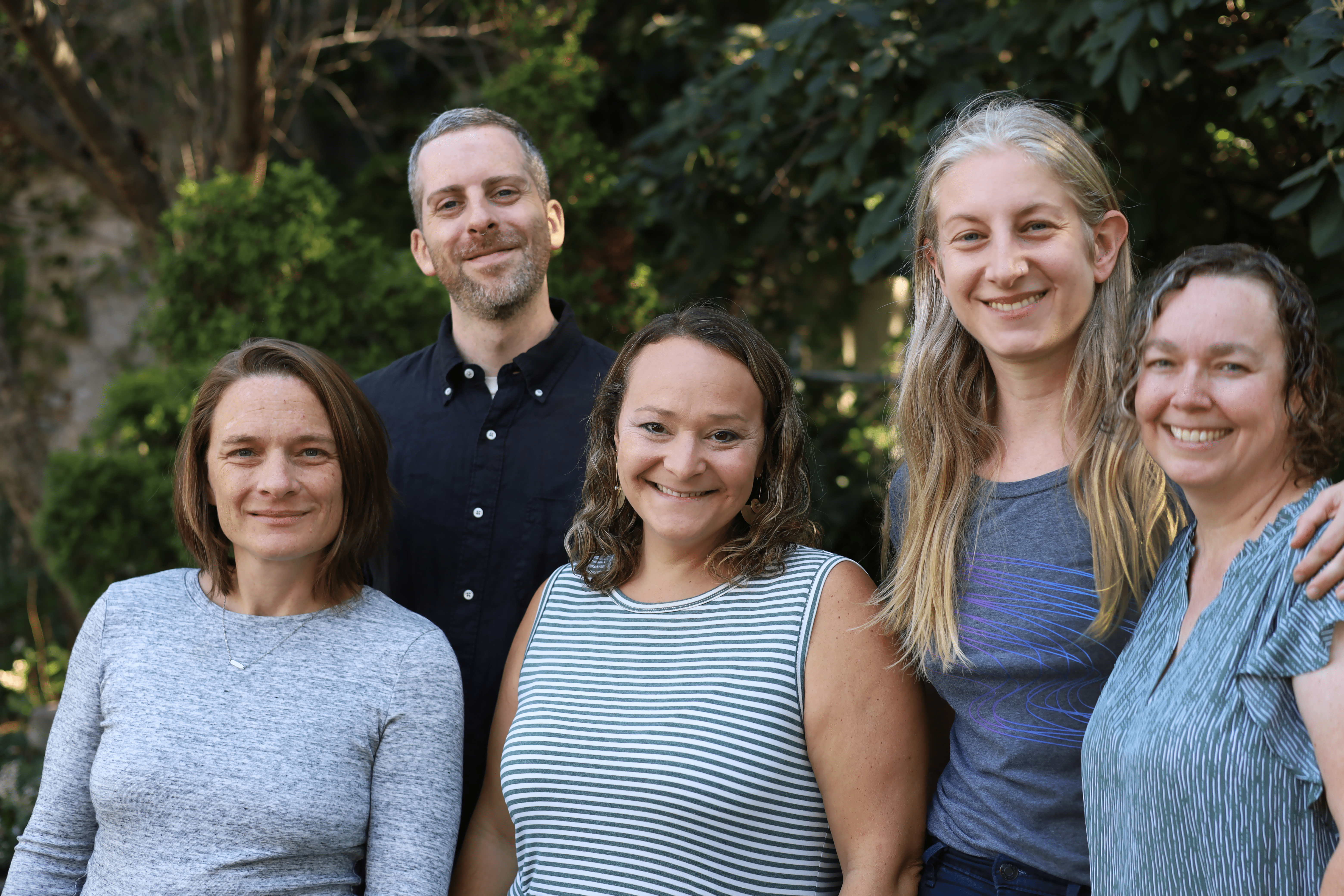 Five people standing in front of trees