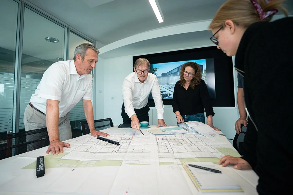 Team von Fries Architekten bei der gemeinsamen Planung eines Bauprojekts im modernen Architekturbüro.