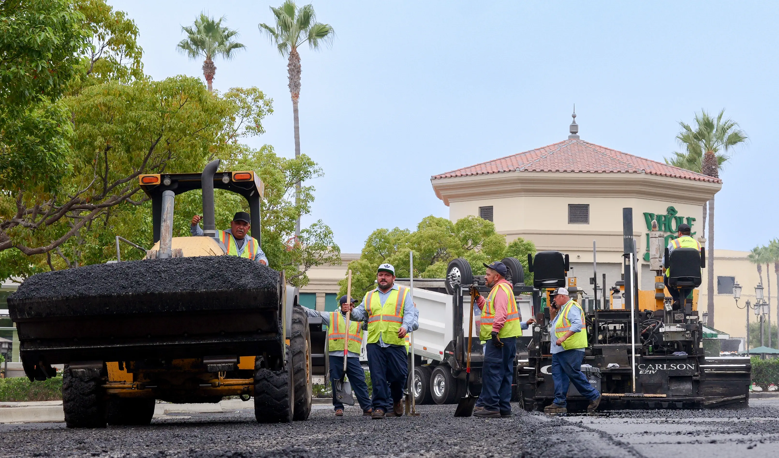 Busy asphalt project with paving machine, shoveling, front end loader equipment