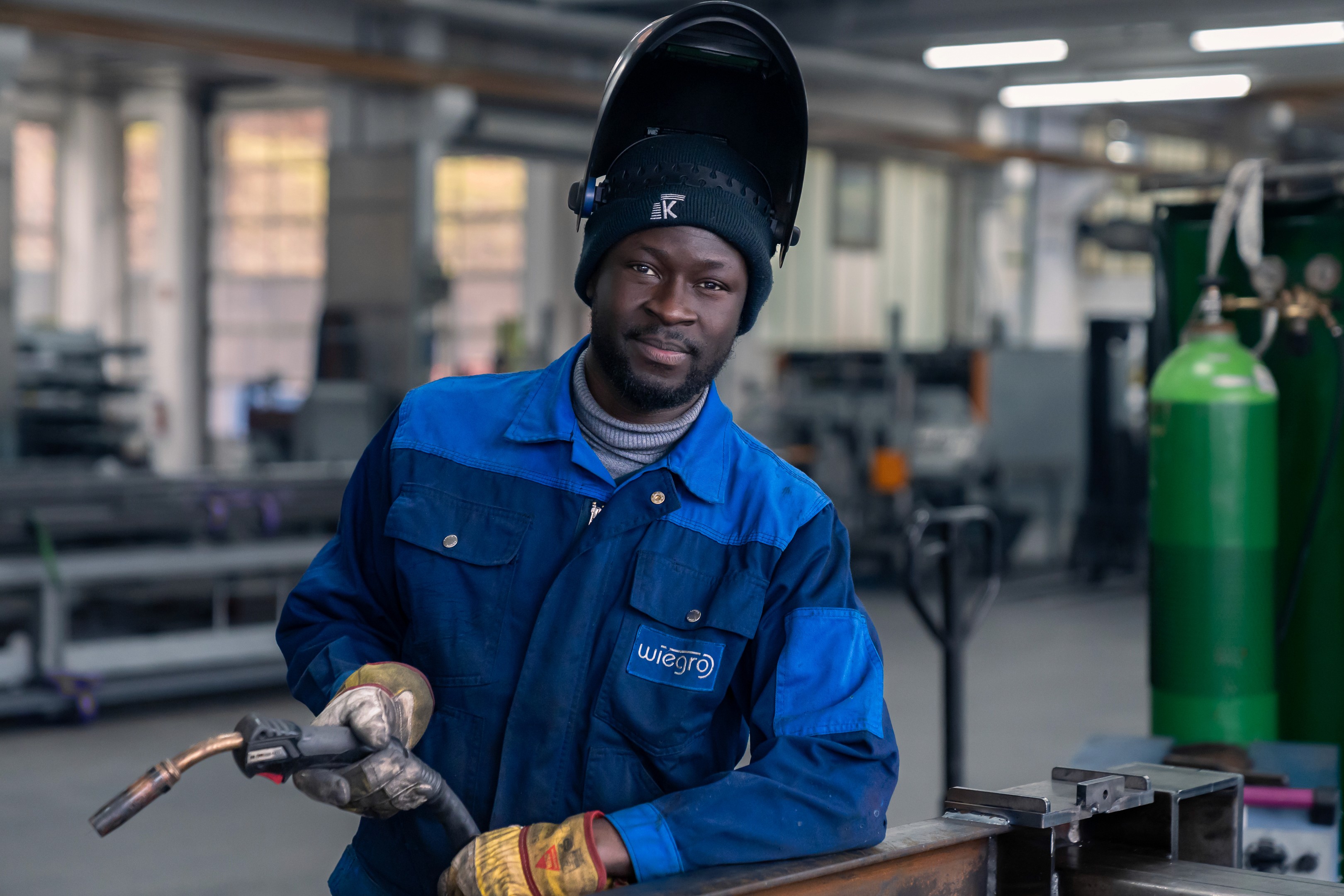man in orange and black vest wearing white helmet holding yellow and black power tool