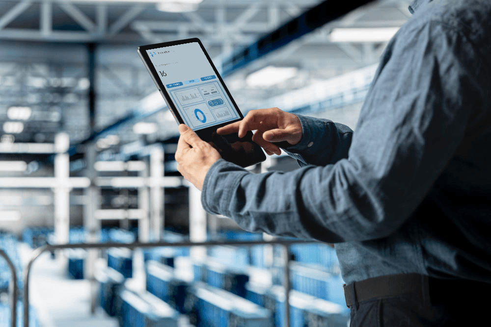 Hands holding a tablet displaying analytics dashboards and performance charts, representing real-time operational insights.